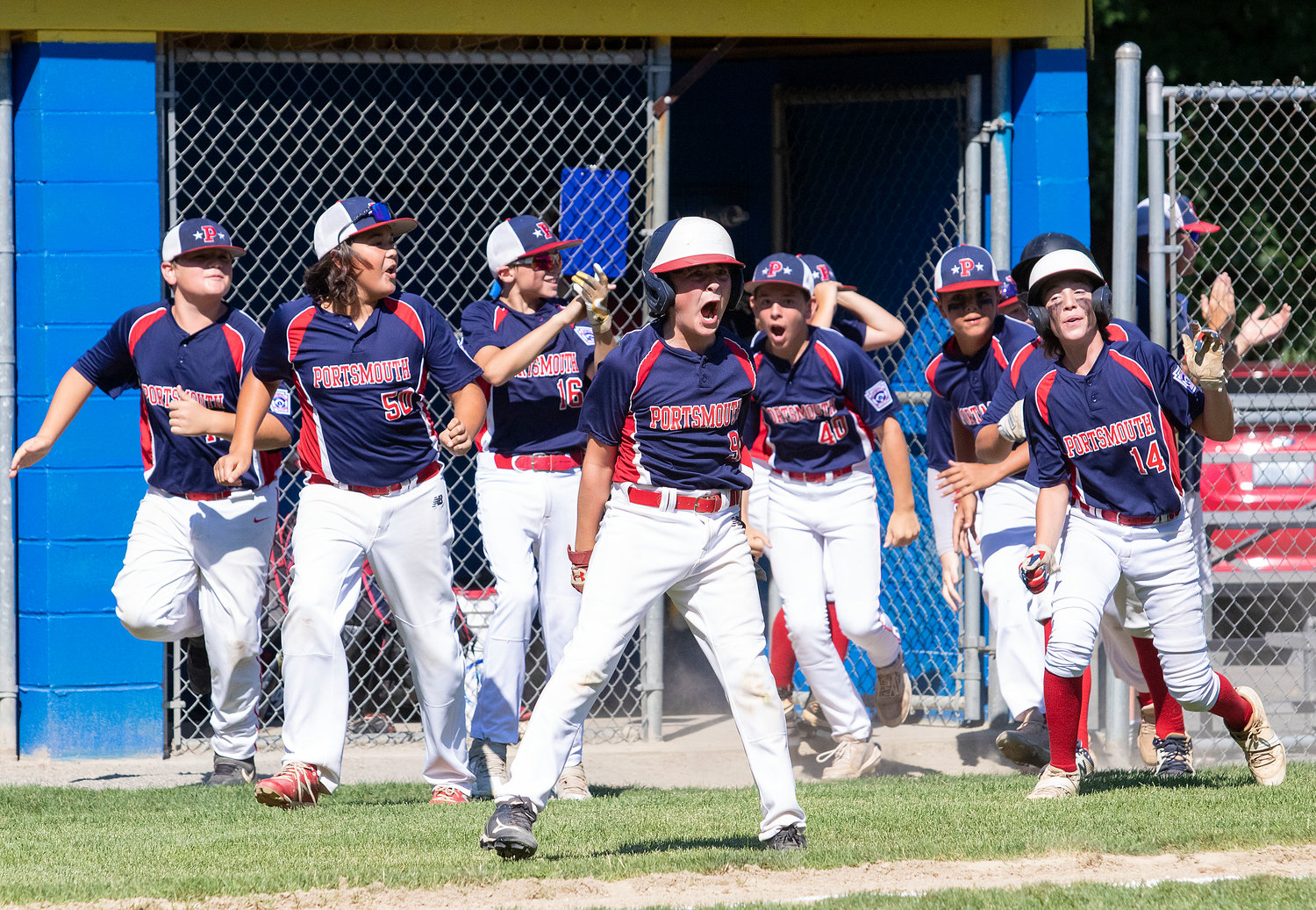 Members of the Portsmouth Little League Major All-Stars team wait to greet Tyler Boiani at home plate after the three-hitter smashed a homer over the centerfield fence to give his team a 2-0 lead against Cumberland in the state tournament on Saturday.