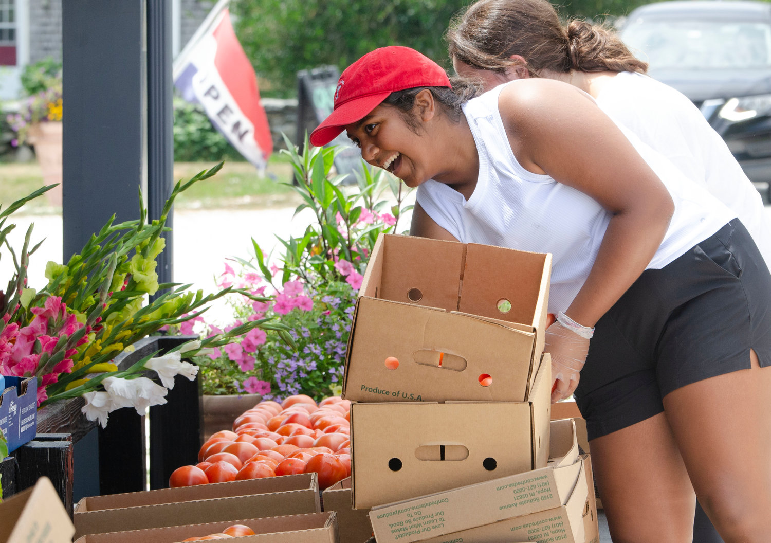 Kyra shankar, 17, (left) and Lucy Rodriguez, 15, place produce on the floor for customers at Young Family Farm in Little Compton on Friday. 