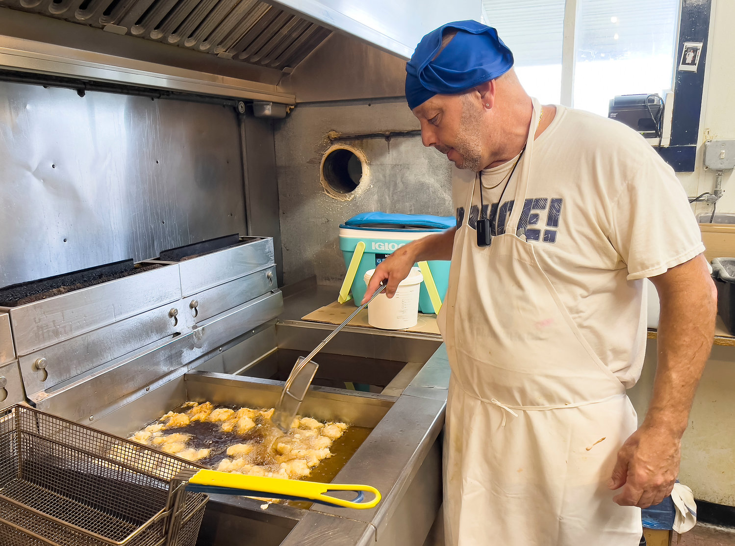 Robert Pires, the kitchen manager and head chef at Flo’s Drive-In on Park Avenue, prepares a batch of clamcakes inside the shack’s small kitchen, which often hits 110 degrees. “You don’t get a break here. We just have to keep on working through it,” he said.