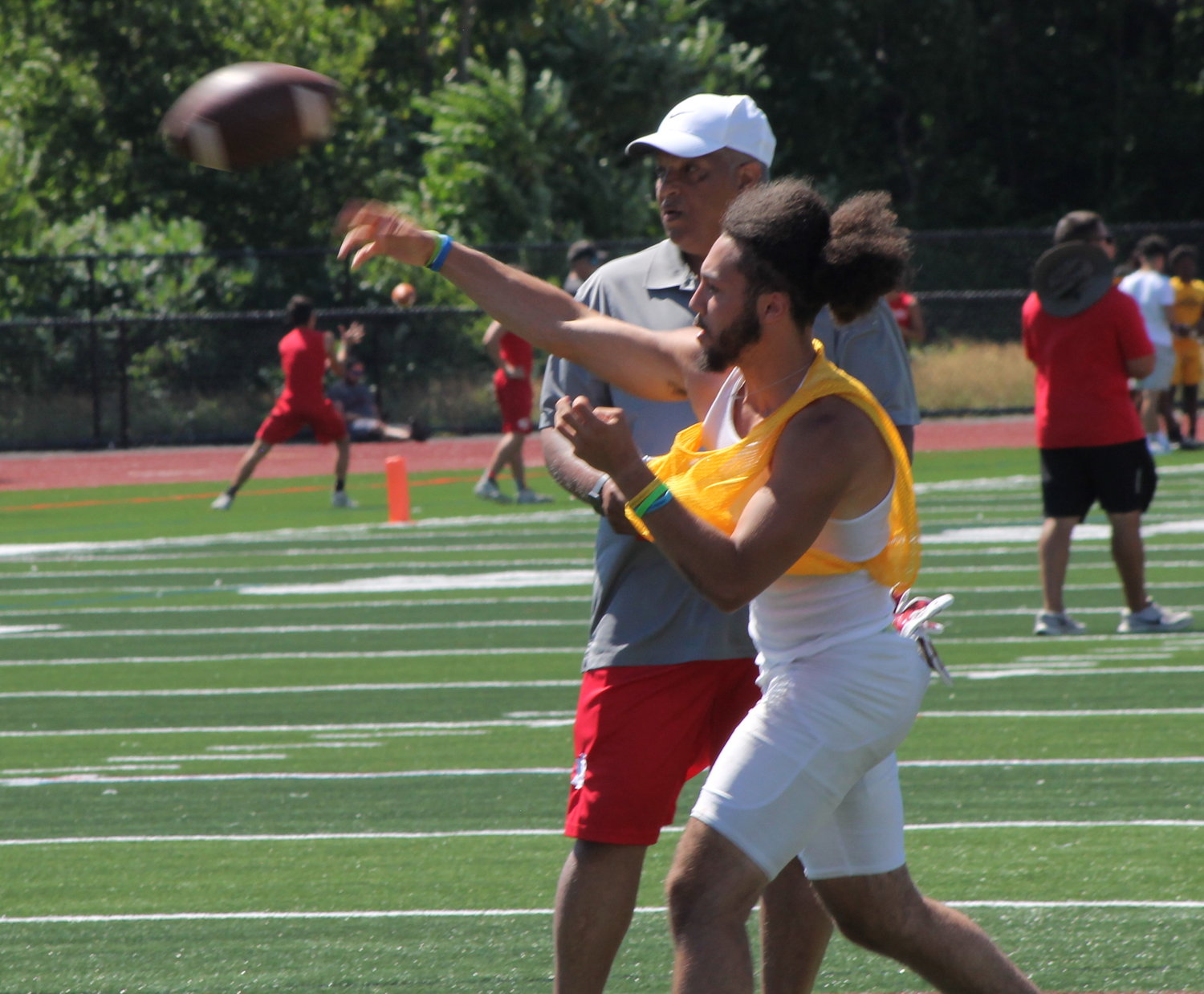 EPHS quarterback Isaac Fox throws a pass under the watchful eye of assistant coach Rondie Almeida