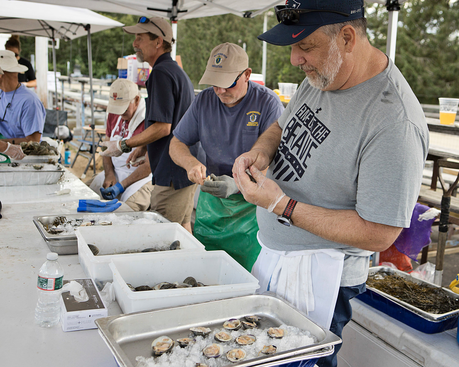 Gary Tripp (left) and Jeff Abrams shuck quahogs Saturday. The raw bar was named in memory of the late Gary Sherman, the former shellfish constable for Westport who passed away last month.
