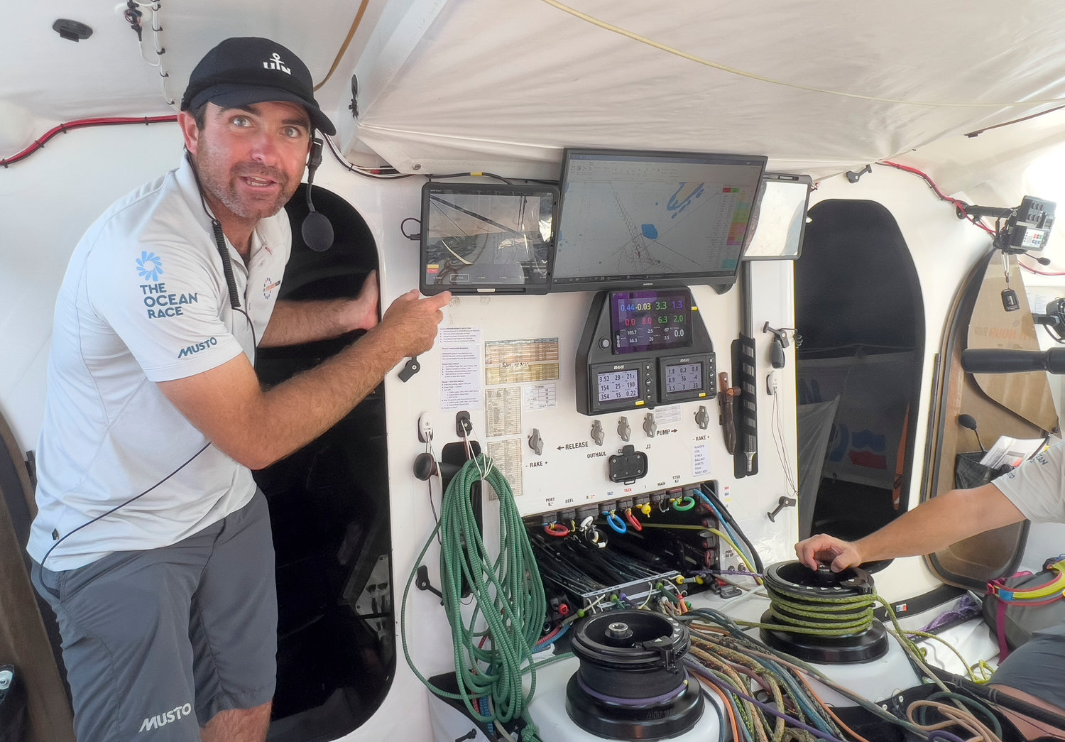 Skipper Charlie Enright (left) speaks about Mãlama’s cutting edge technical equipment, touch screen computers and an autopilot system that assists the crew with maneuvers and helming as well as charting courses.