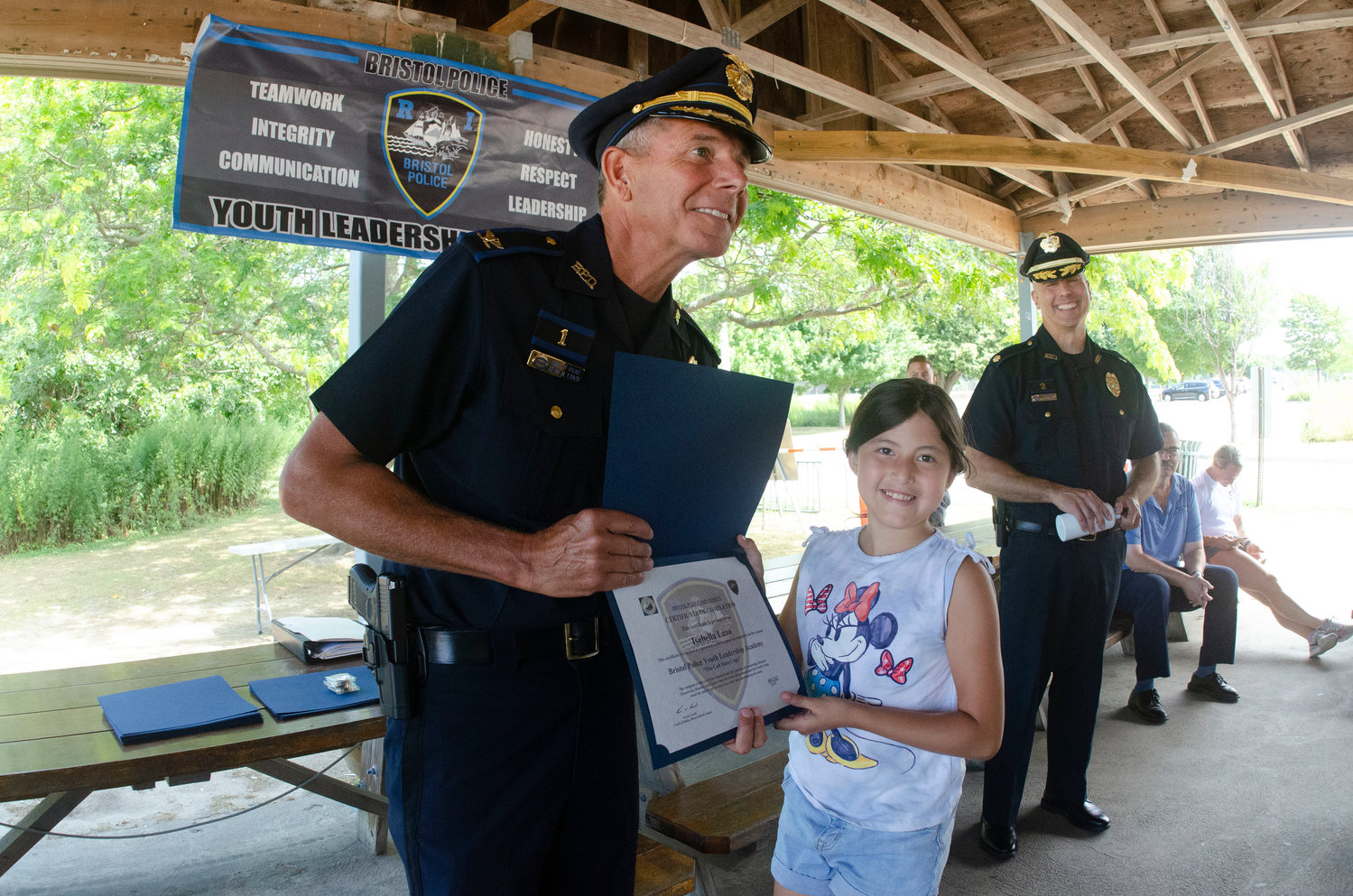 Bristol Police Chief Kevin Lynch (left) and Major Brian Burke pose with Isabelle Lazo after she received a certificate for passing the leadership academy at the town beach on Friday.