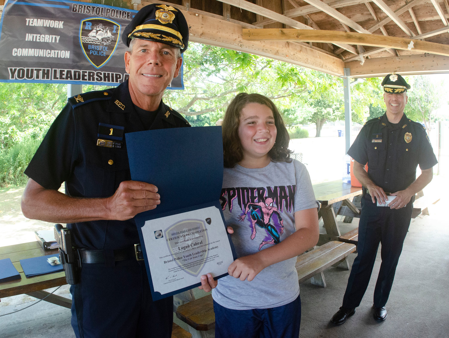 Bristol Police Chief Kevin Lynch (left) and Major Brian Burke pose with Logan Cabral after she received a certificate for passing the leadership academy at the town beach on Friday.