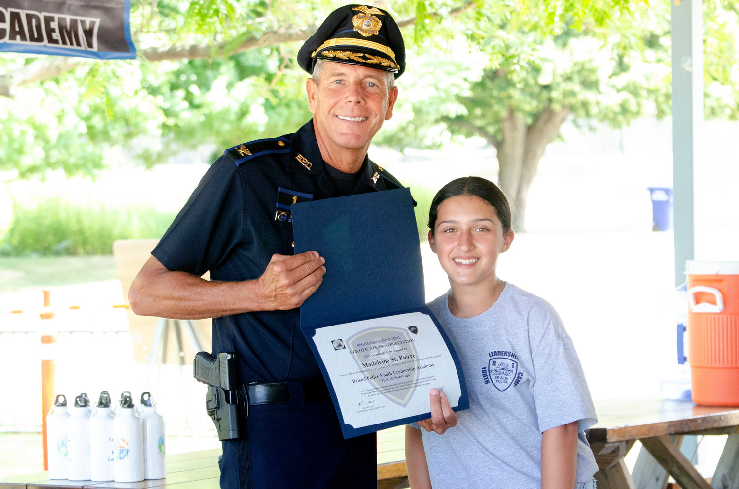 Bristol Police Chief Kevin Lynch and Madeleine St. Pierre take a photo after she received a certificate for passing the leadership academy at the town beach on Friday.