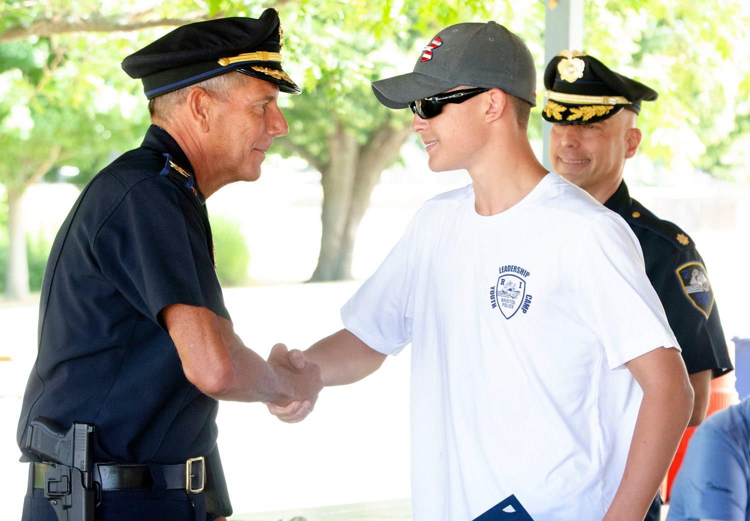 Bristol Police Chief Kevin Lynch (left) shakes hands with Robert Ennis after he gave him a certificate of appreciation at leadership academy at the town beach on Friday.