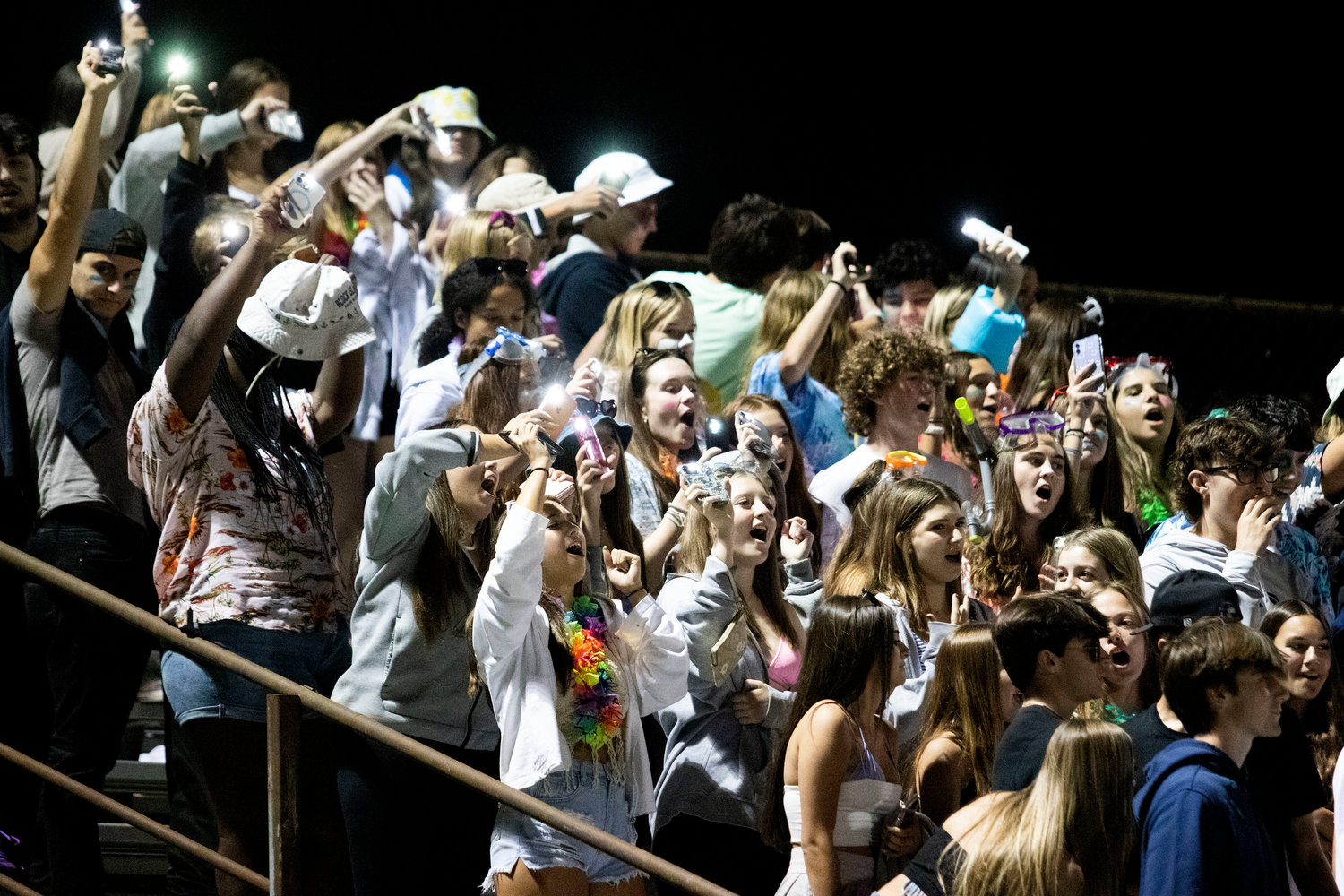 The Dog Pound wave their lit phone lights as they sing during the game.