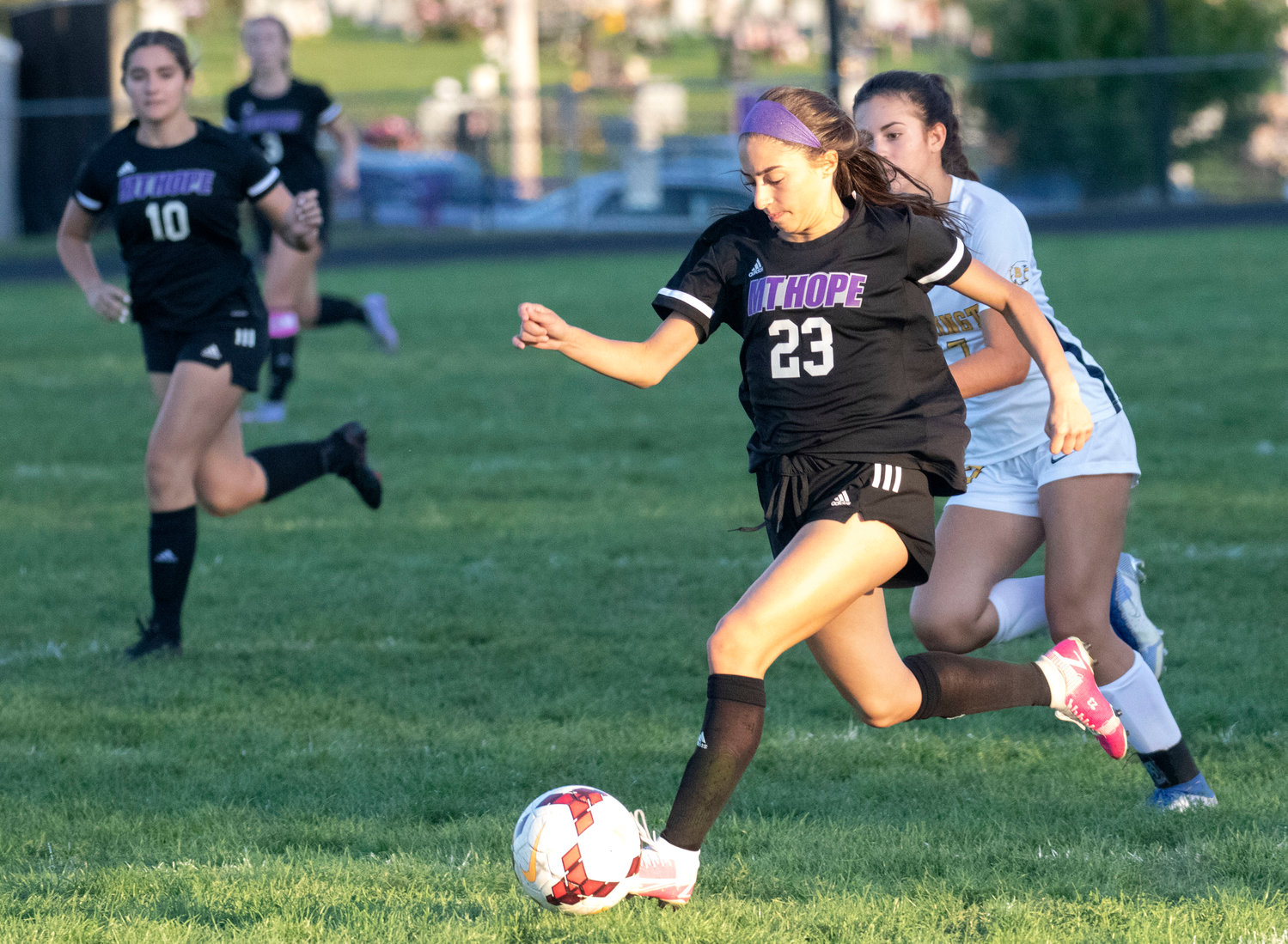 Junior midfielder Hannah Rezendes speeds up field with the ball and a defender in tow.