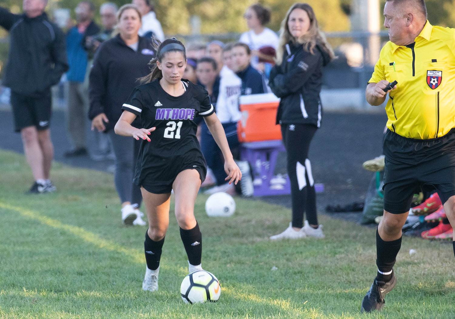 Midfielder Lilliana Redman dribbles up the sideline by the Huskies bench.