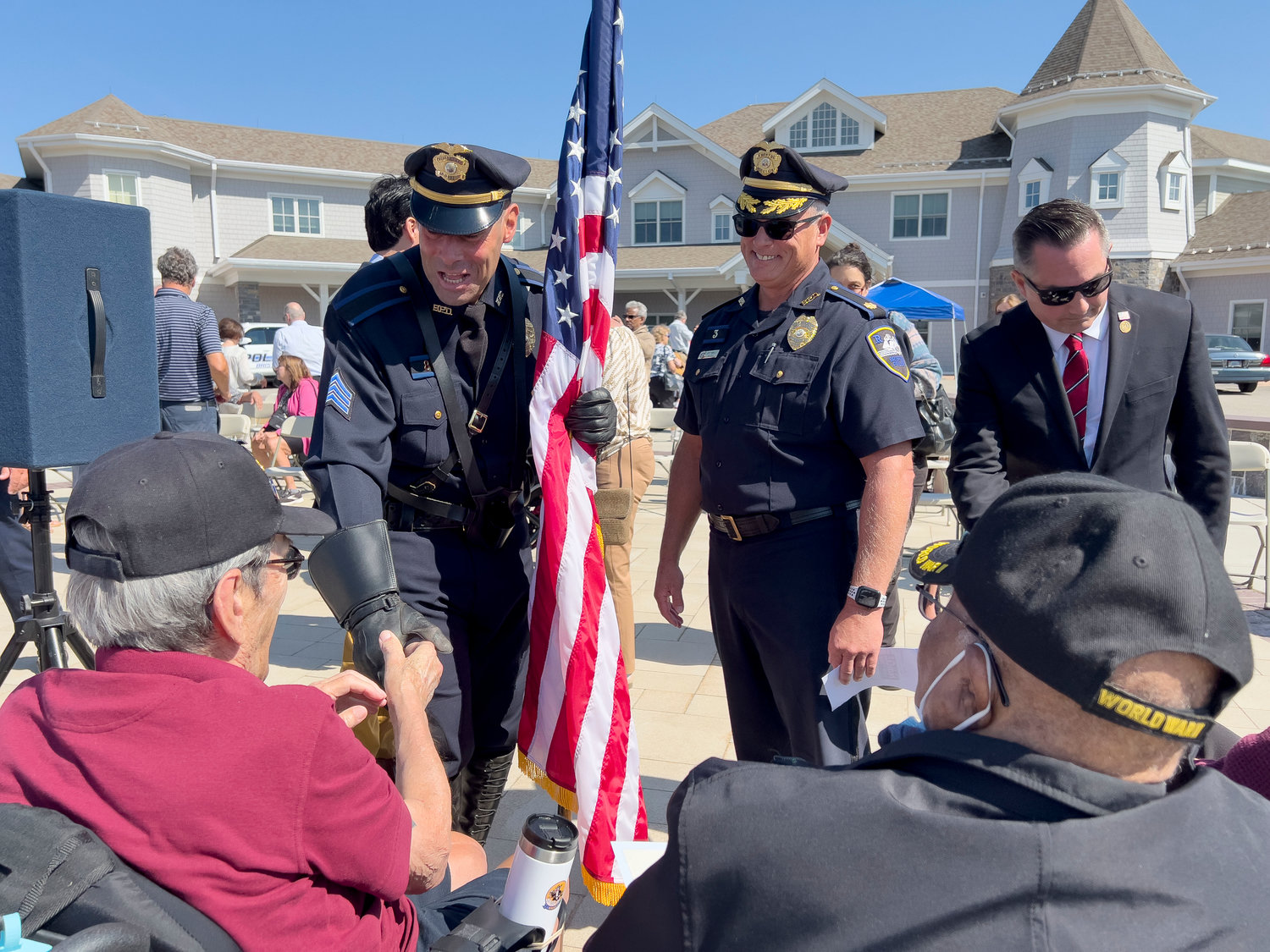 Bristol Police Sgt. Paul Medeiros, Commander Scott McNally and town councilman Aaron Ley shake hands with honored veterans as Bristol is named a Purple Heart town during a ceremony at the RI Veterans Home on Friday.