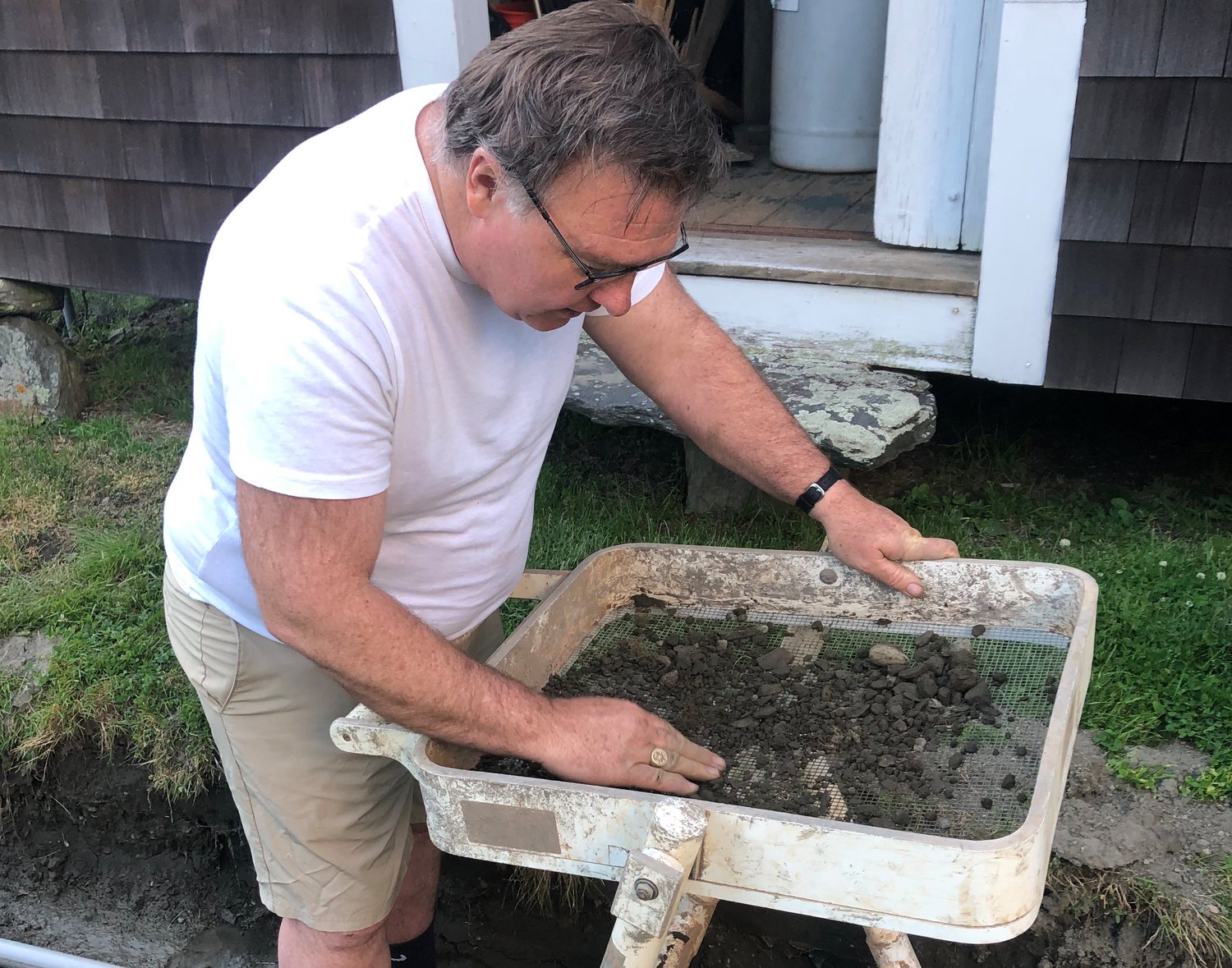 Tim O'Toole works a sifter to recover small artifacts from a construction trench at the Wilbor House.