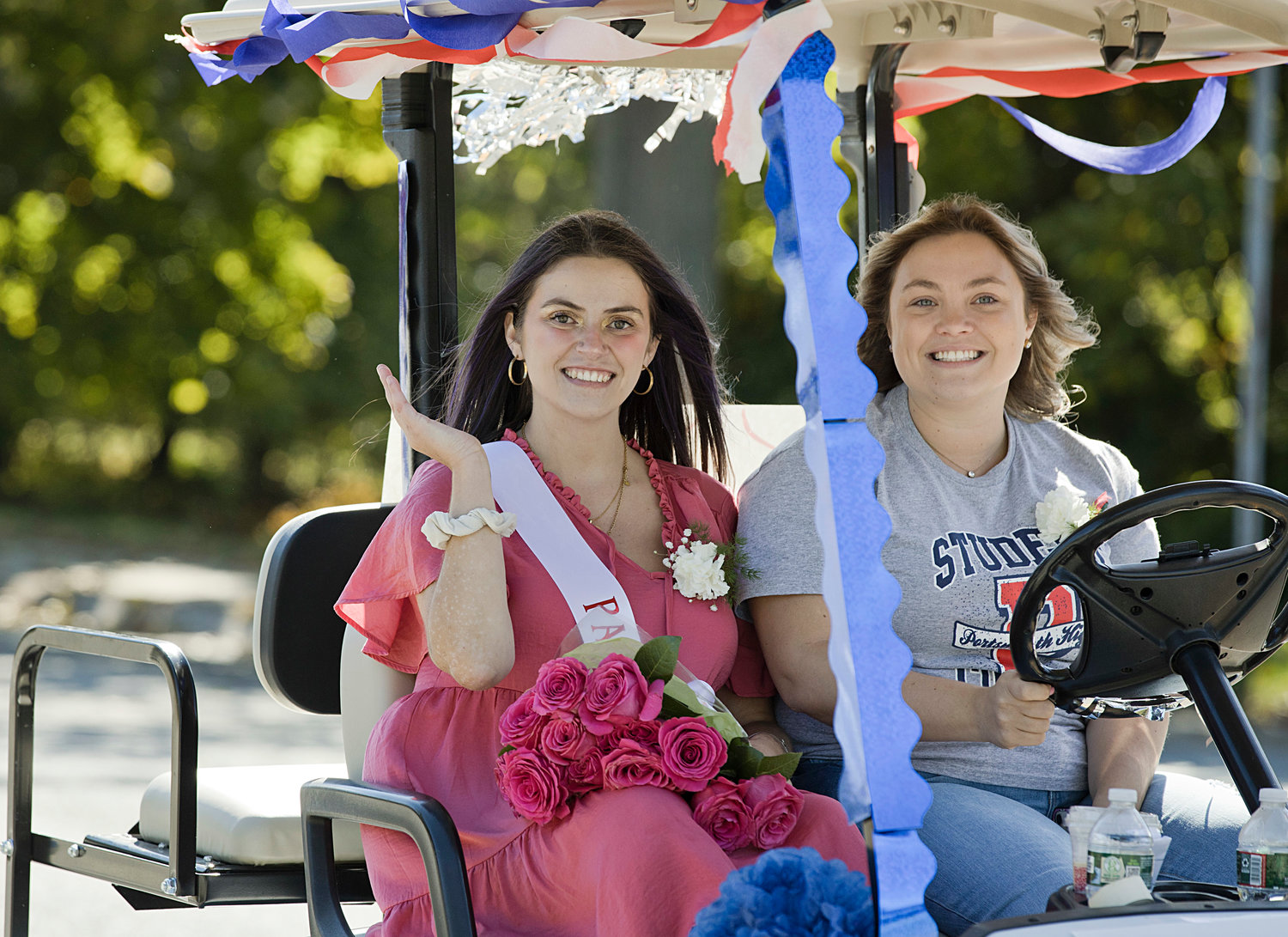 Homecoming Parade Grand Marshal Kristina Caragianis waves to spectators while being driven along the parade route by Hailey Abbott.