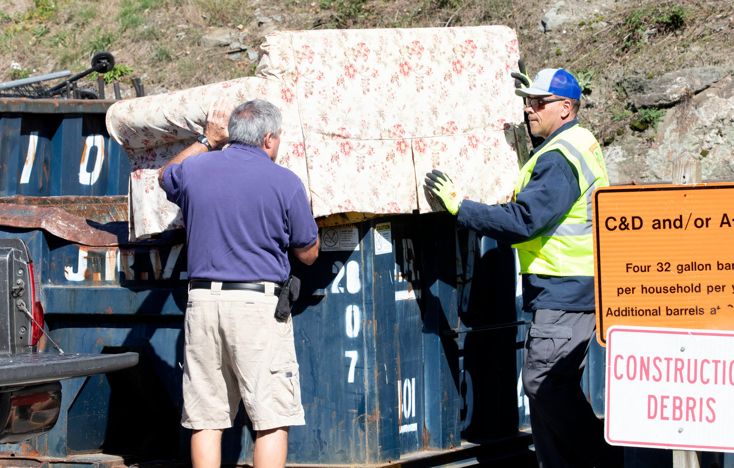 Transfer station worker John Potter (right) helps a customer heave a sofa into a bin on Tuesday.