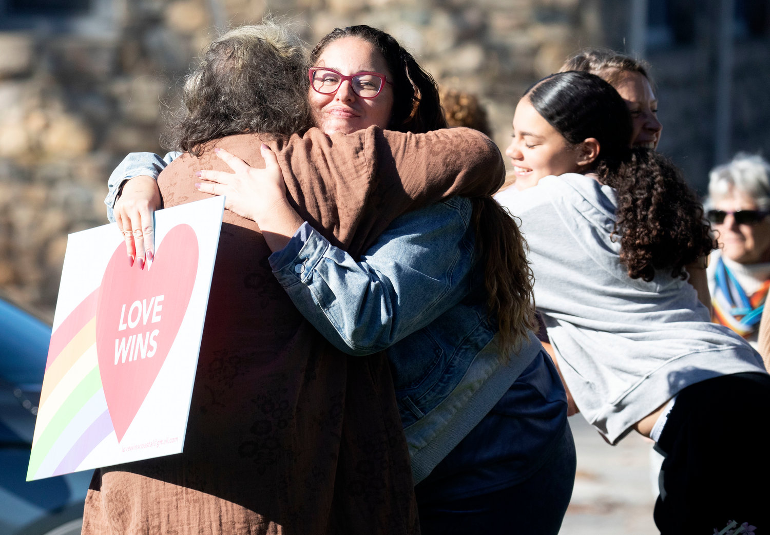 Megan Wordell (middle) and others hug during a rally held in Little Compton Sunday afternoon. The rally was organized by Love Wins as a counterpoint to an incendiary mailer sent out late last week to Little Compton residents, which criticized progressive politics and Democrats, and called out council and school committee members for their stances on sex education, the flying of the Pride flag, and other issues.