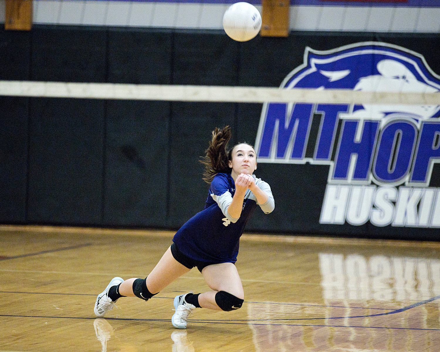 Gwenyth Tucker dives under the the ball while receiving a serve from a Lincoln opponent.