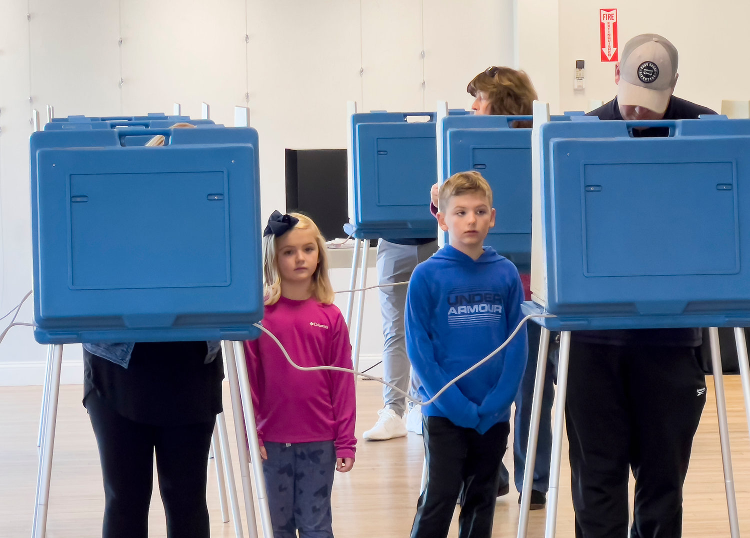 Kora Brule, 6, and her brother Roman, 8, wait patiently as their parents, Britt and Jason Brule, vote at The CFP Arts, Wellness and Community Center in Common Fence Point Tuesday morning.