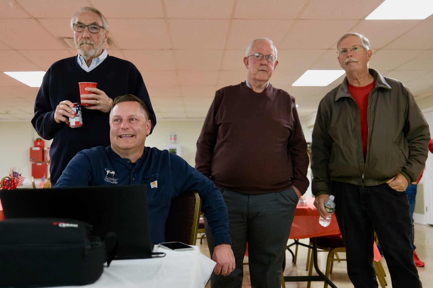 Town Council member Keith Hamilton (sitting), who was re-elected, watches the polling numbers come in Tuesday night at at St. John’s Lodge No. 1, which served as Republican election headquarters. Behind him are (from left) Joe Lorenz, chairman of the Republican Town Committee; Larry Fitzmorris, president of Portsmouth Concerned Citizens; and David Gleason, who was voted back onto the council.