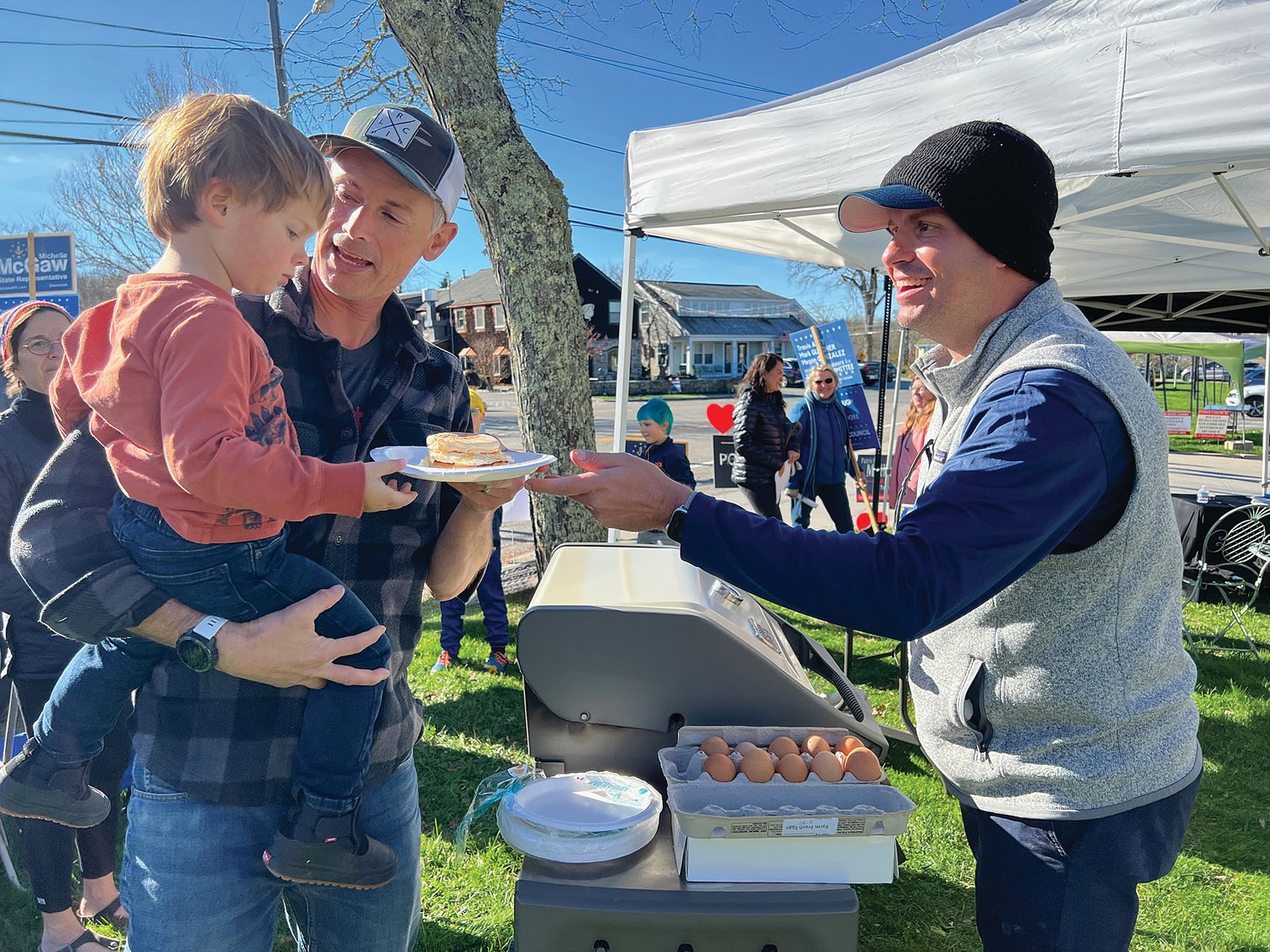 Incumbent school committee member and Democratic Town Committee Chairman Travis Auty serves voters sandwiches from his grill near the Wilbur McMahon School Tuesday morning.