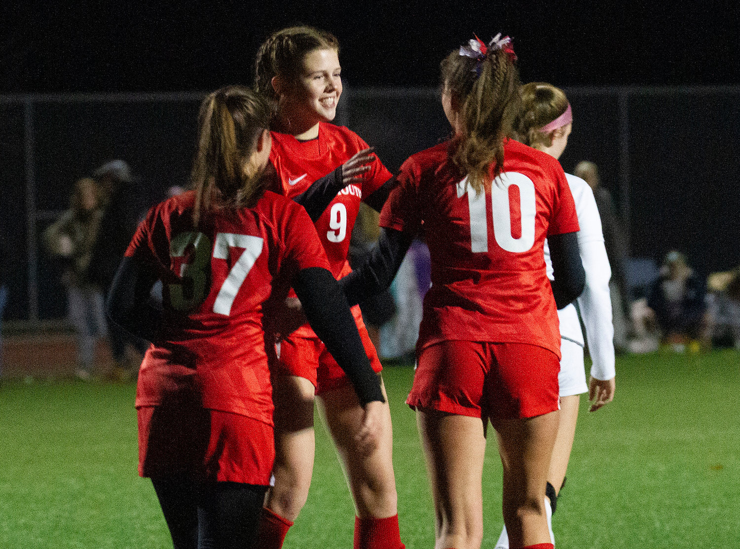 Evelyn Shuster, Poppy Jelly, and Kaitlin Roche (from left) celebrate after Roche booted in a penalty kick in the second half to make the score 5-0.