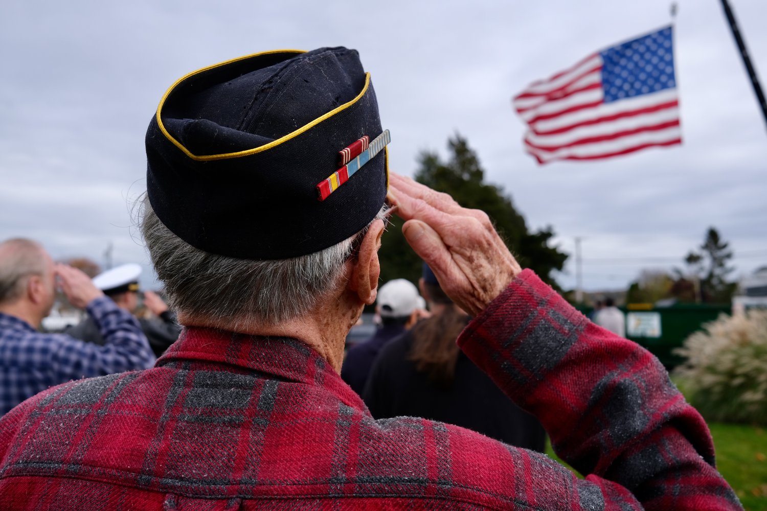 George Cushman, a 91-year-old Army veteran who served time in Korea, salutes the American flag as it’s hoisted up by a crane at Thrive Coffee House in Island Park this morning. The restaurant honored veterans with a special ceremony that featured a short parade and a performance by the Portsmouth High School Marching Band.