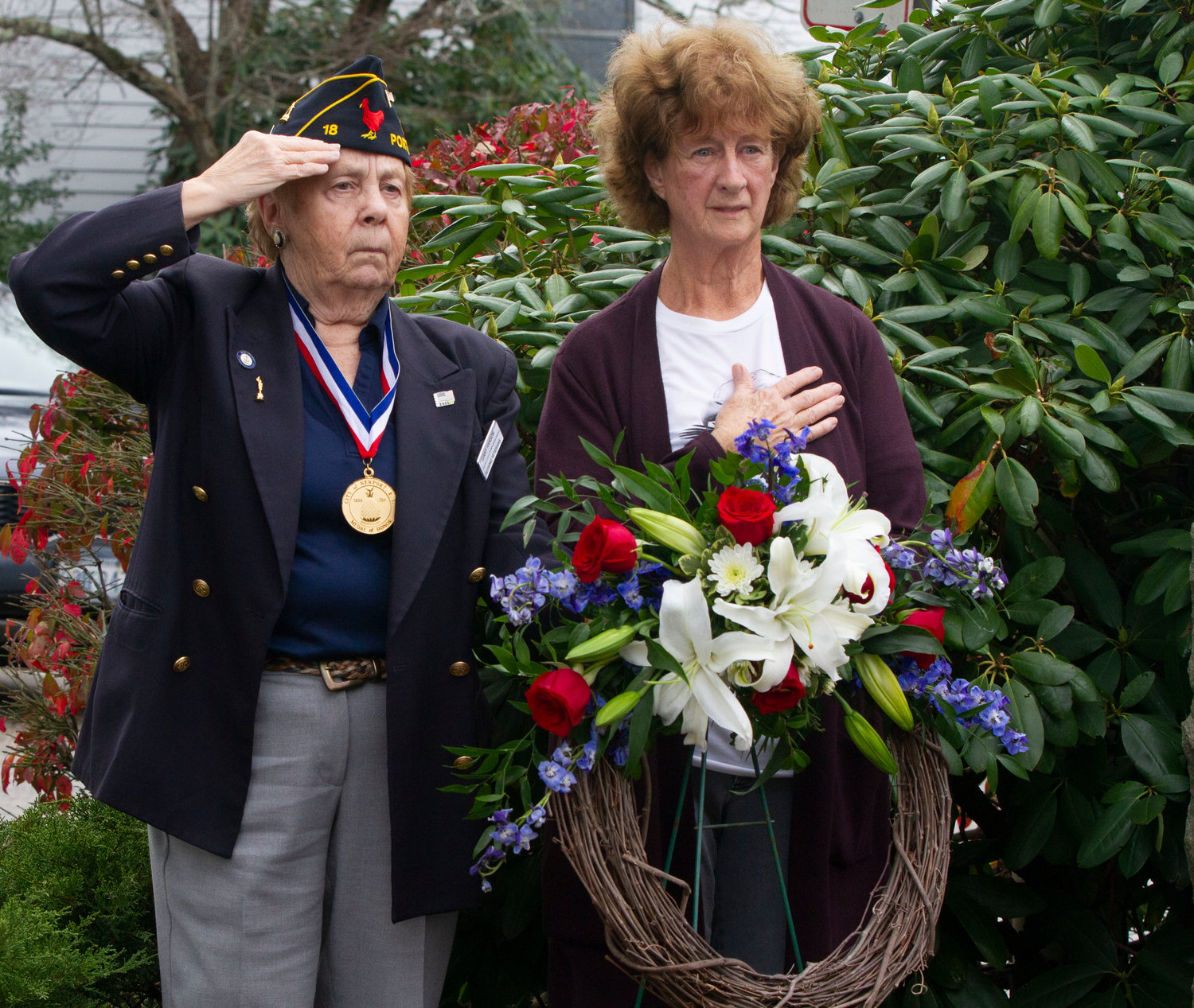 Ginny Hansen (left) and Carolyn Evans-Carbery pause for the playing of "Taps" during the outdoor portion of the ceremony at Town Hall on Friday.
