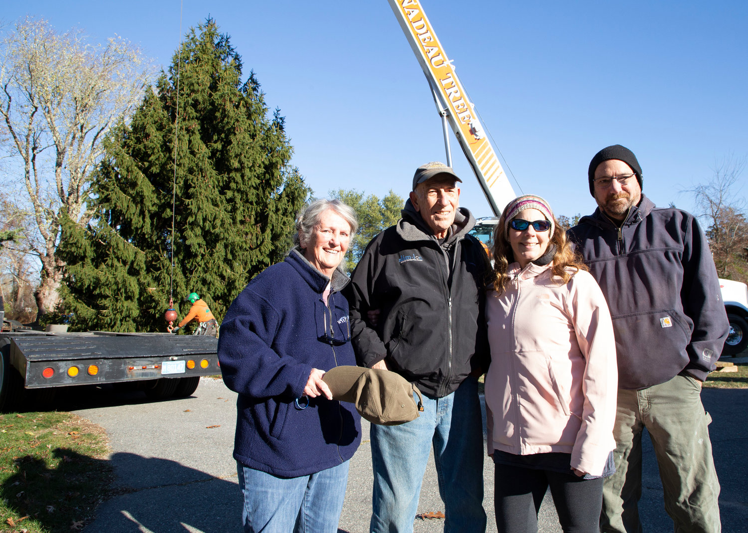 Pat Butler (left), husband Tom, and their son TJ Butler and his wife Julie Reitzas pose in front of the tree before it's cut down.