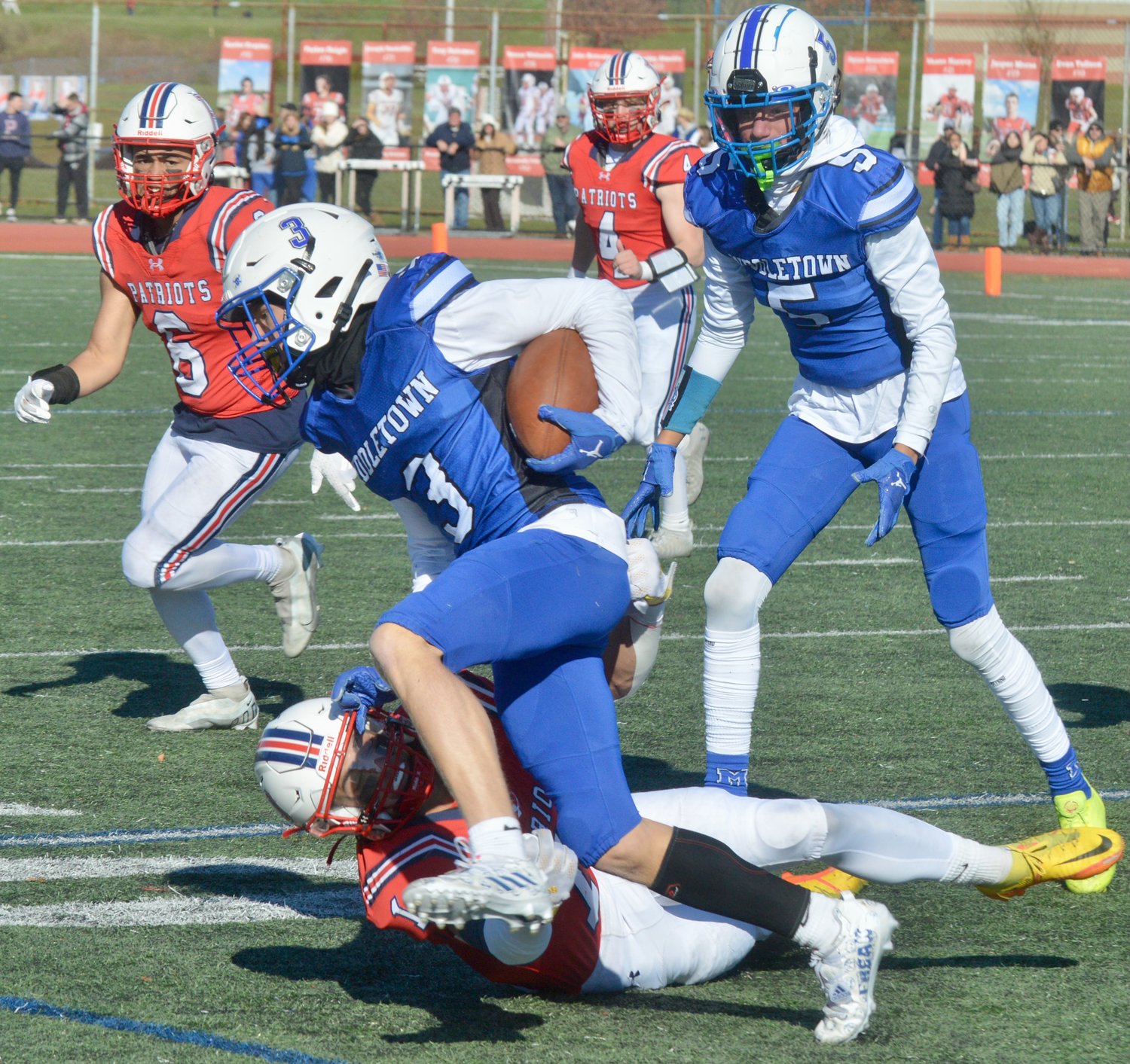 Carson Conheeny (bottom) attempts to bring down Middletown receiver Cameron Miller after a pass play.
