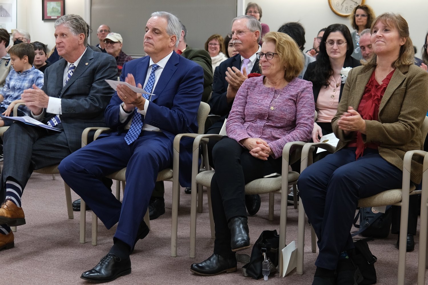 Gov. Daniel McKee, R.I. Attorney General Peter Neronha, Rep. Terri Cortvriend, and Rep. Michelle McGaw (from left) listen to the ceremony from the front row. Between Neronha and Cortvriend in the second row is David Gleason, who won a seat on the Town Council and was waiting to be sworn in by the governor.