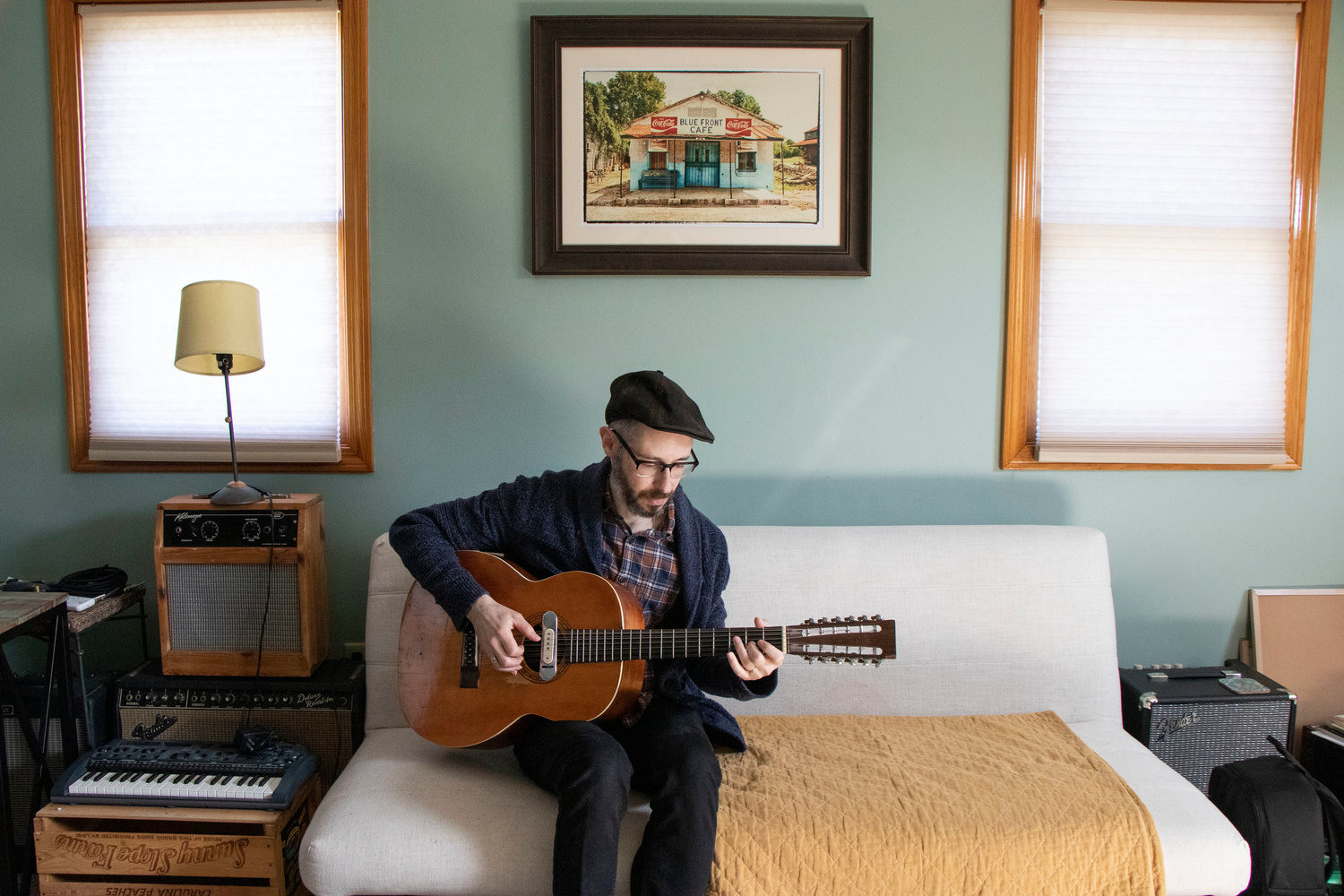 Ryan Lee Crosby in his home practice space in Island Park. Above him is a photo of the Blue Front Cafe, an old juke joint in Bentonia, Miss., where he has performed.