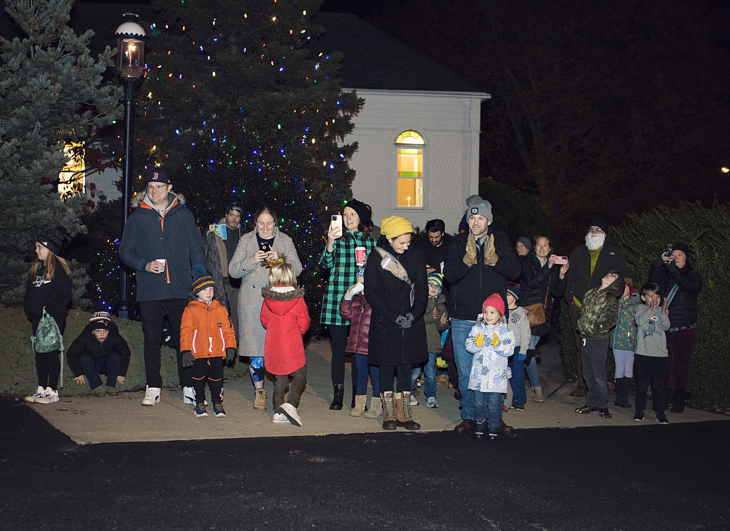 Families clap for Santa as he makes his way toward the library during Portsmouth’s tree-lighting event.