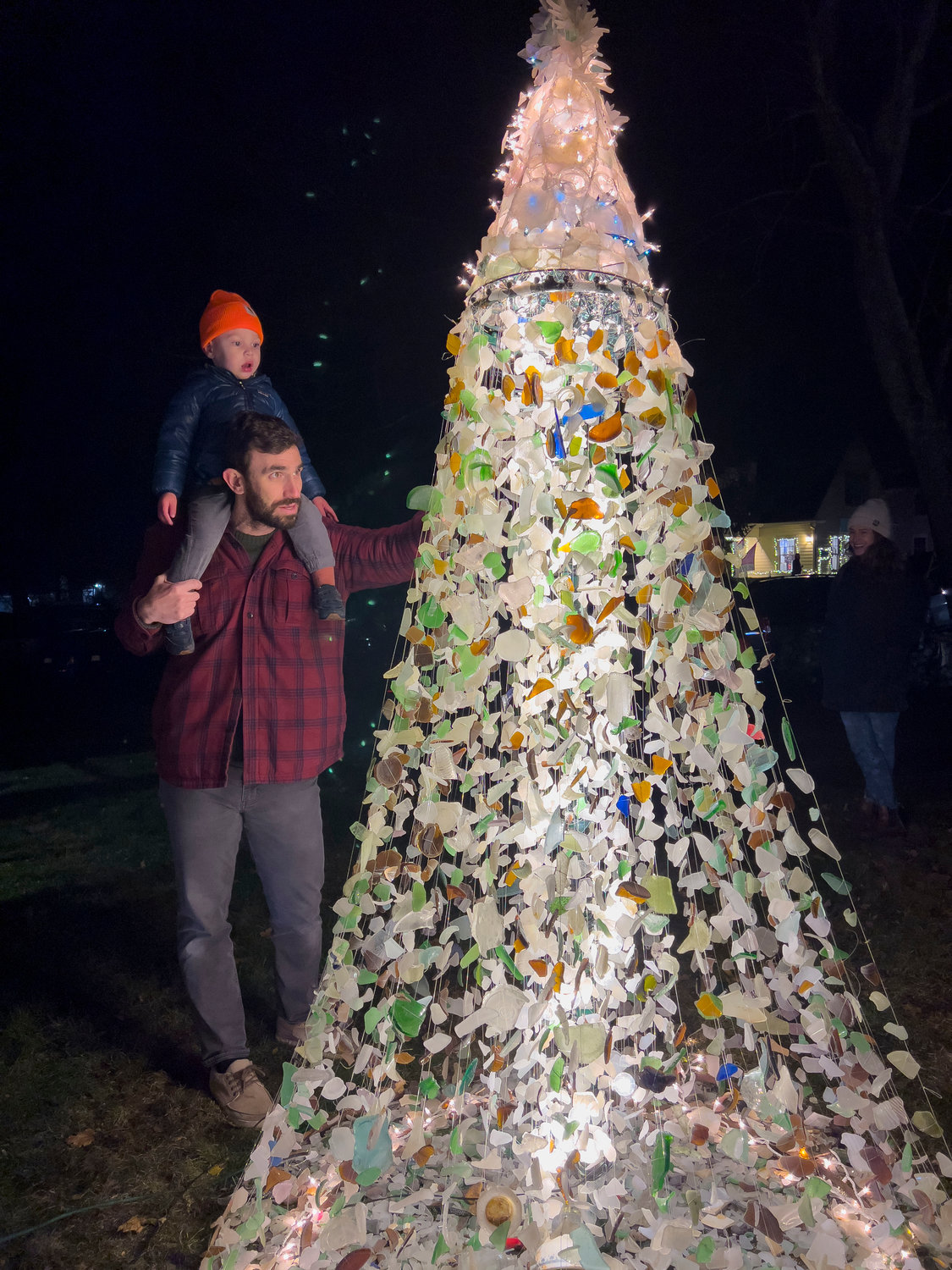 Sean Conlon and son, Remi, 2, gaze at the colorful tree made of locally found sea glass by John Viveiros and wife, Snooky.