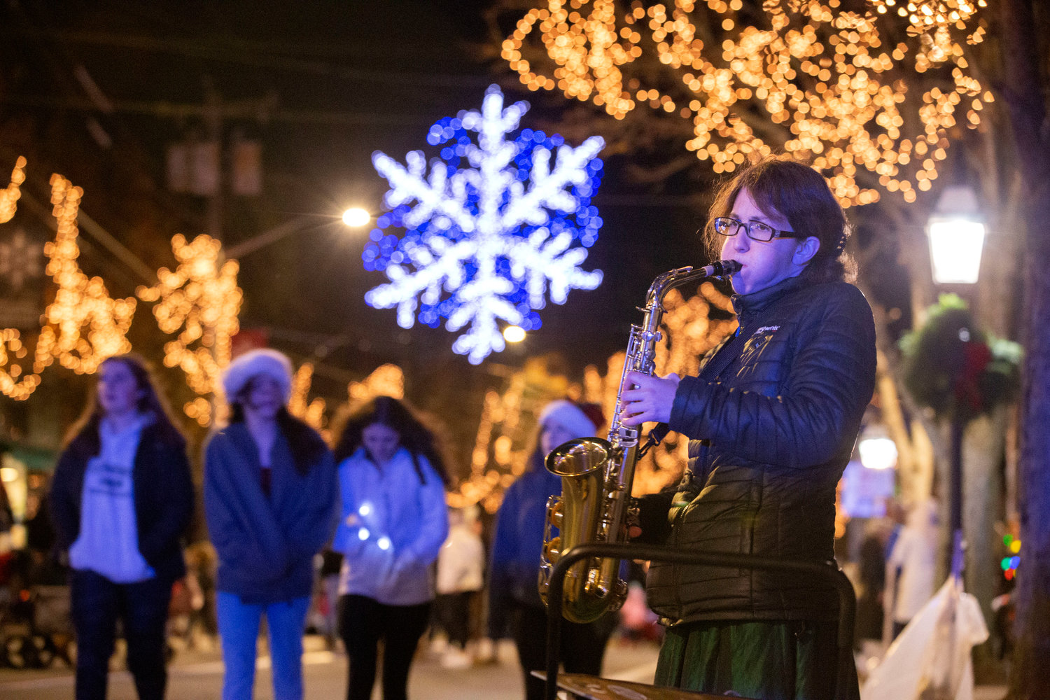 Cass Michael, 43, plays joy to the world on her alto sax on Hope Street as residents walk home. She had been coming to the grand illumination for years with friend Steve Parella of Bristol, who recently passed away due to illness.