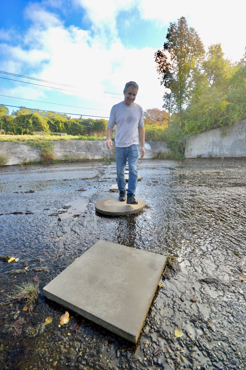 Stephen Luce walks over a stream located on the western edge of Melville Park. Some of the flat stones had to be replaced after a heavy rainfall washed them away.