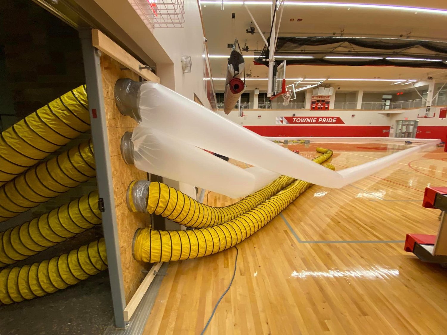 A translucent plastic tube was used by Clean Care New England to pump heated air into the gym from a large generator located just outside to aid in the evaporation efforts.