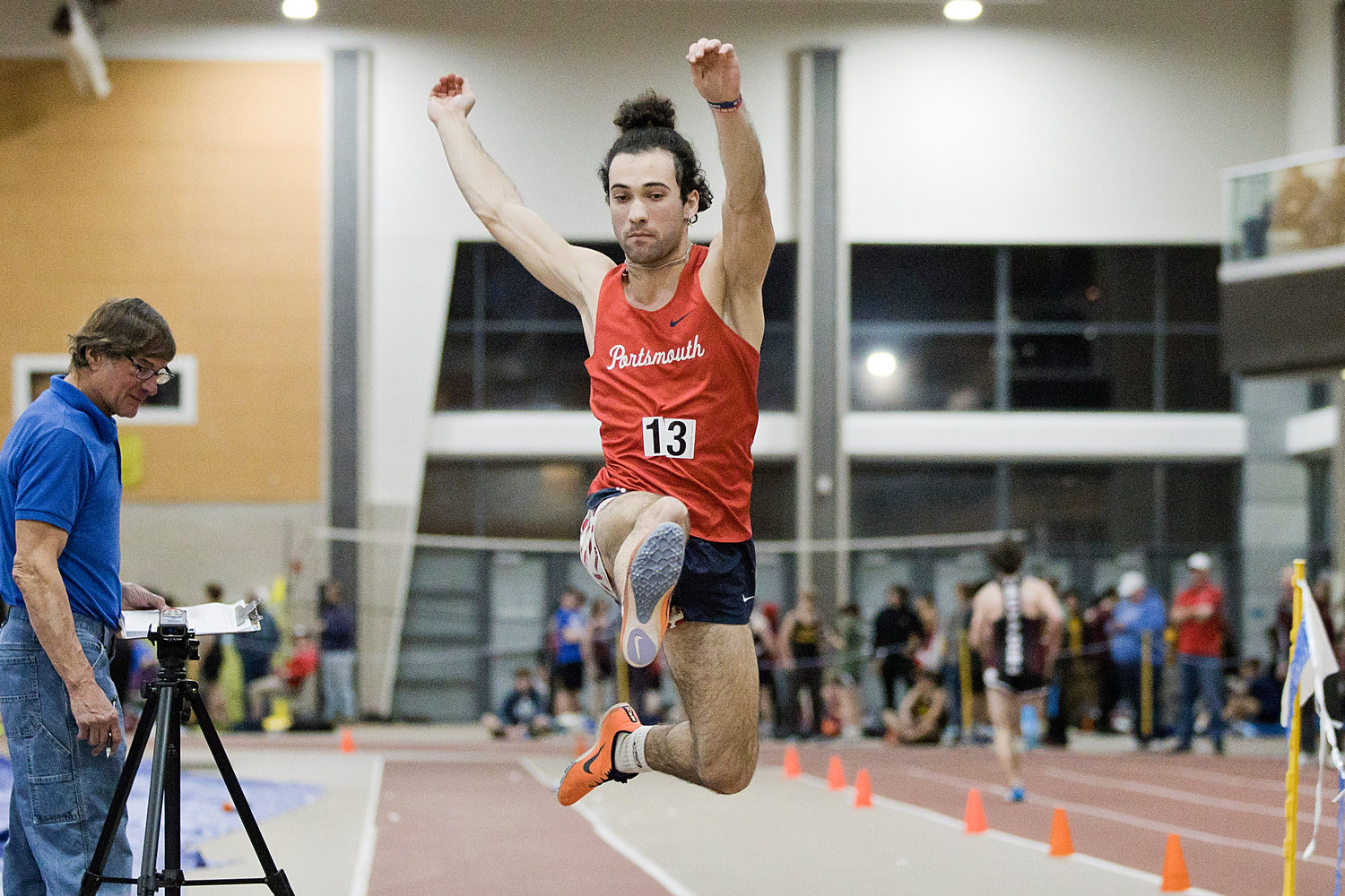 The Patriots’ Nikolai Loyola leaps toward the sand while competing in the long jump.