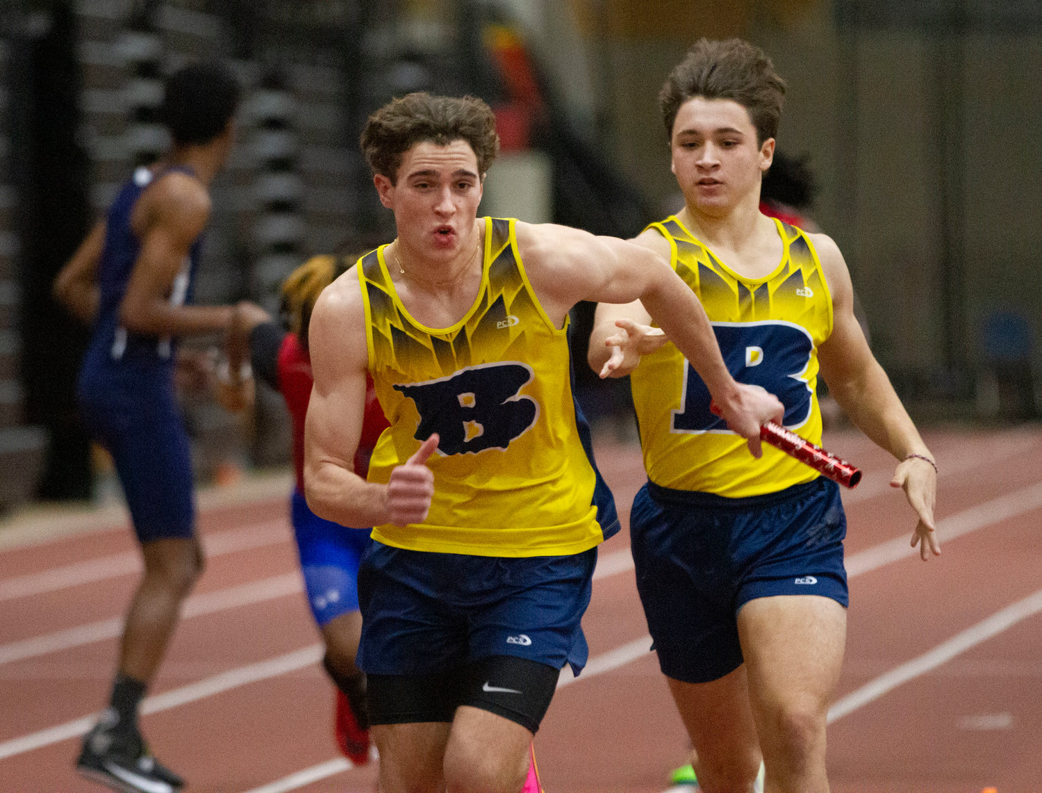Ethan Knight (left), shown taking the baton during a relay event at a previous meet, set a new school record in the 55-meter hurdles during the Metropolitan Division Championships.