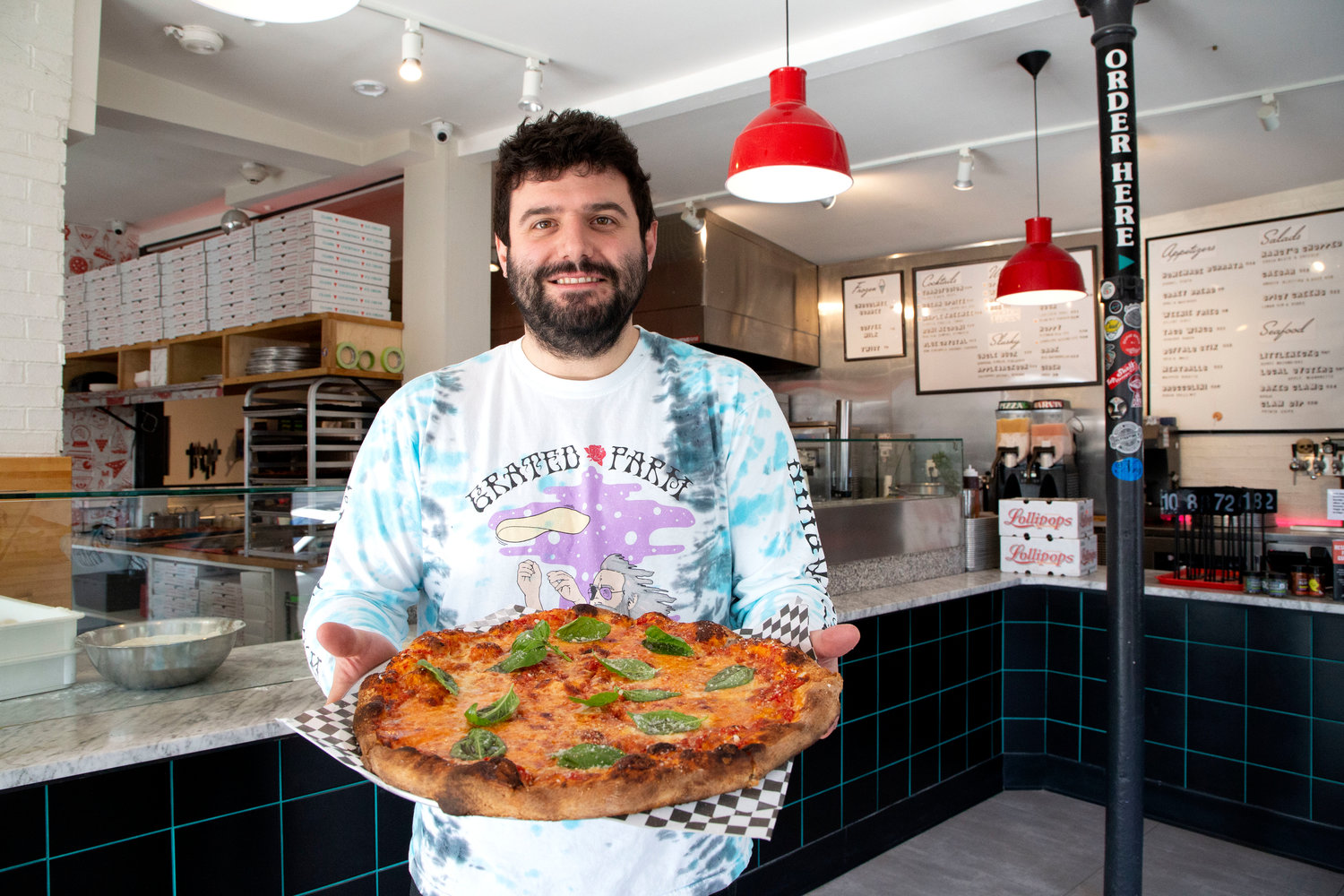 Robert Andreozzi holds up a finished pie inside Pizza Marvin, which specializes in unique pizza and cocktail offerings.