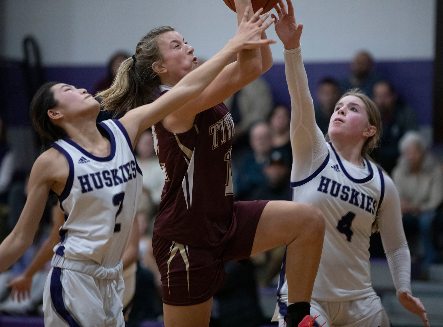 Katie Richardson drives for a layup between Huskies guards Elsa White (left) and Lilly DaSilveira.