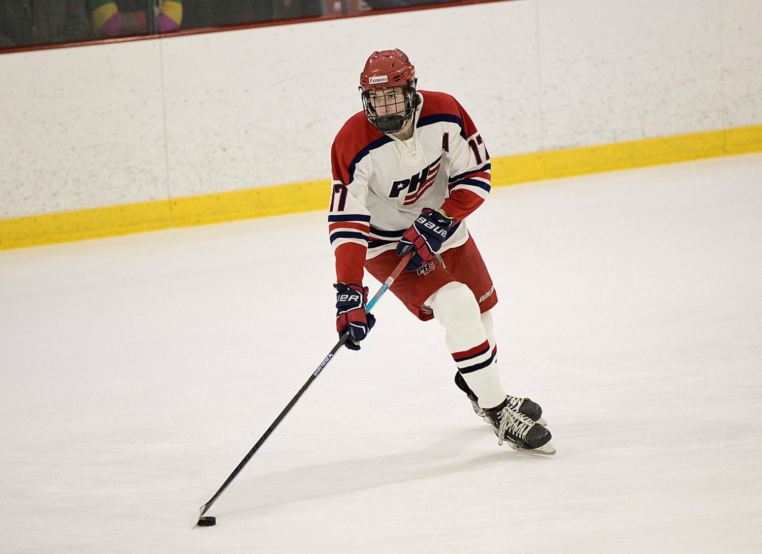 Dan Biello scans the ice for an open teammate while holding the puck for the Patriots.
