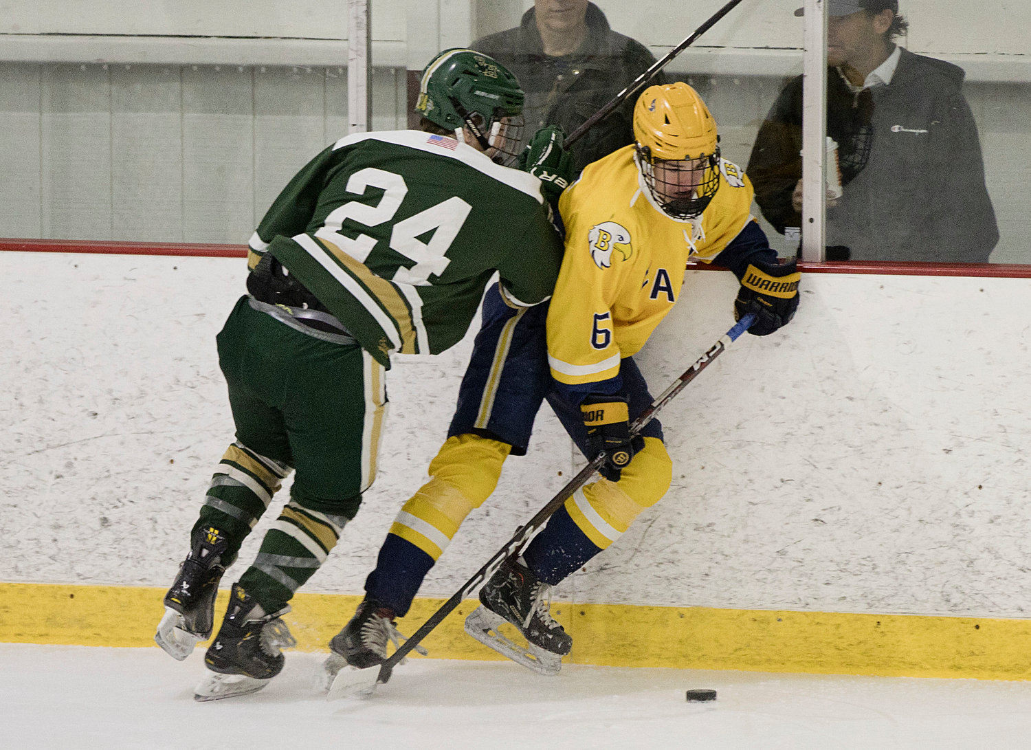Barrington's Adam Gorman is checked into the boards by a Hendricken opponent while retrieving a loose puck.