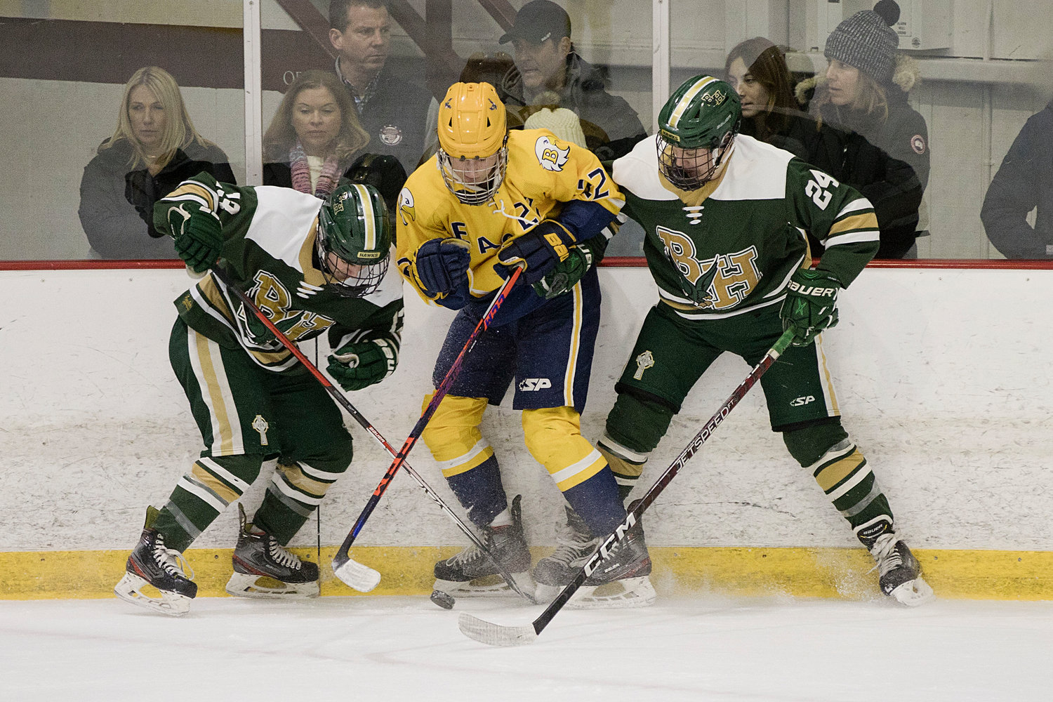 Trevor Snow is sandwiched between a pair of Hendricken opponents while vying for a loose puck.