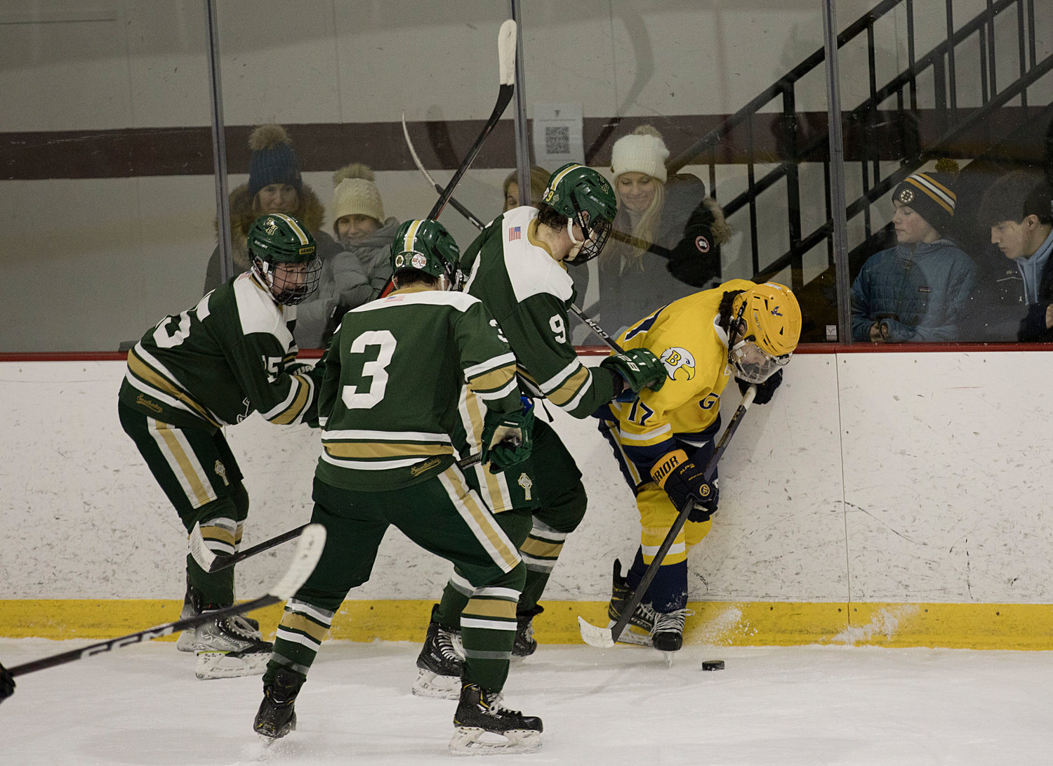 Drake Almeida is pressured by a trio of Hendricken defenders while in control of the puck.