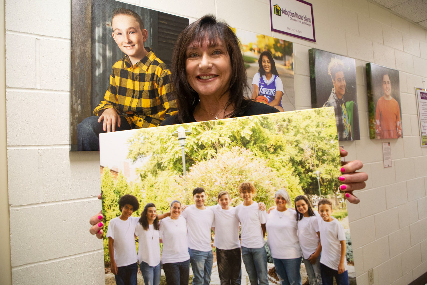 Donna Rivera, Marketing and Communications Director for Adoption Rhode Island, holding a photo of the Rado family, a local adoption success story whose family consists of three biological children and four adopted children.