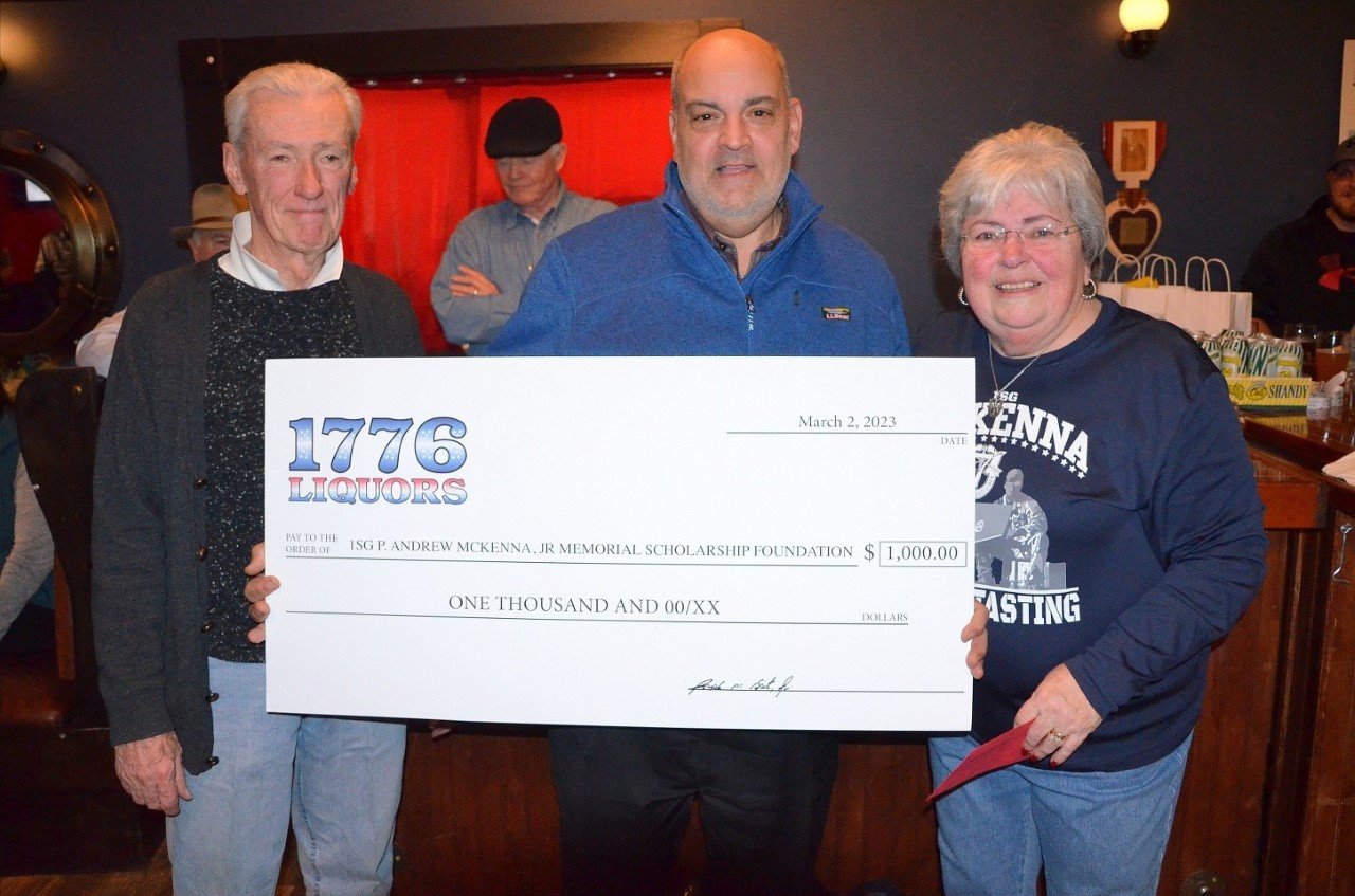 Tom Sousa (center), manager at 1776 Liquors, presents a check for $1,000 to Peter and Carol McKenna during 1st Sgt. Andrew McKenna Fundraiser last Thursday night.