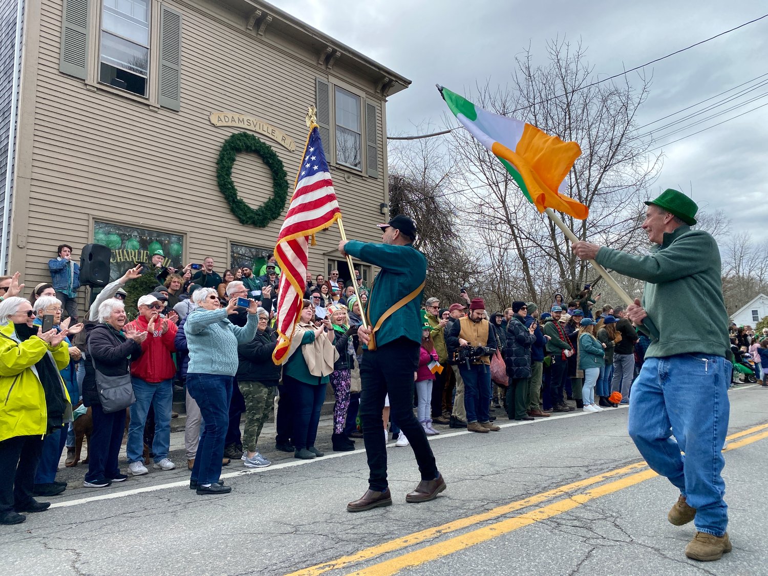 Navy veteran Luke Driver waves the United States flag, and Mike Coffey the Irish, as the parade passes the Kinnane compound in Adamsville Saturday afternoon.