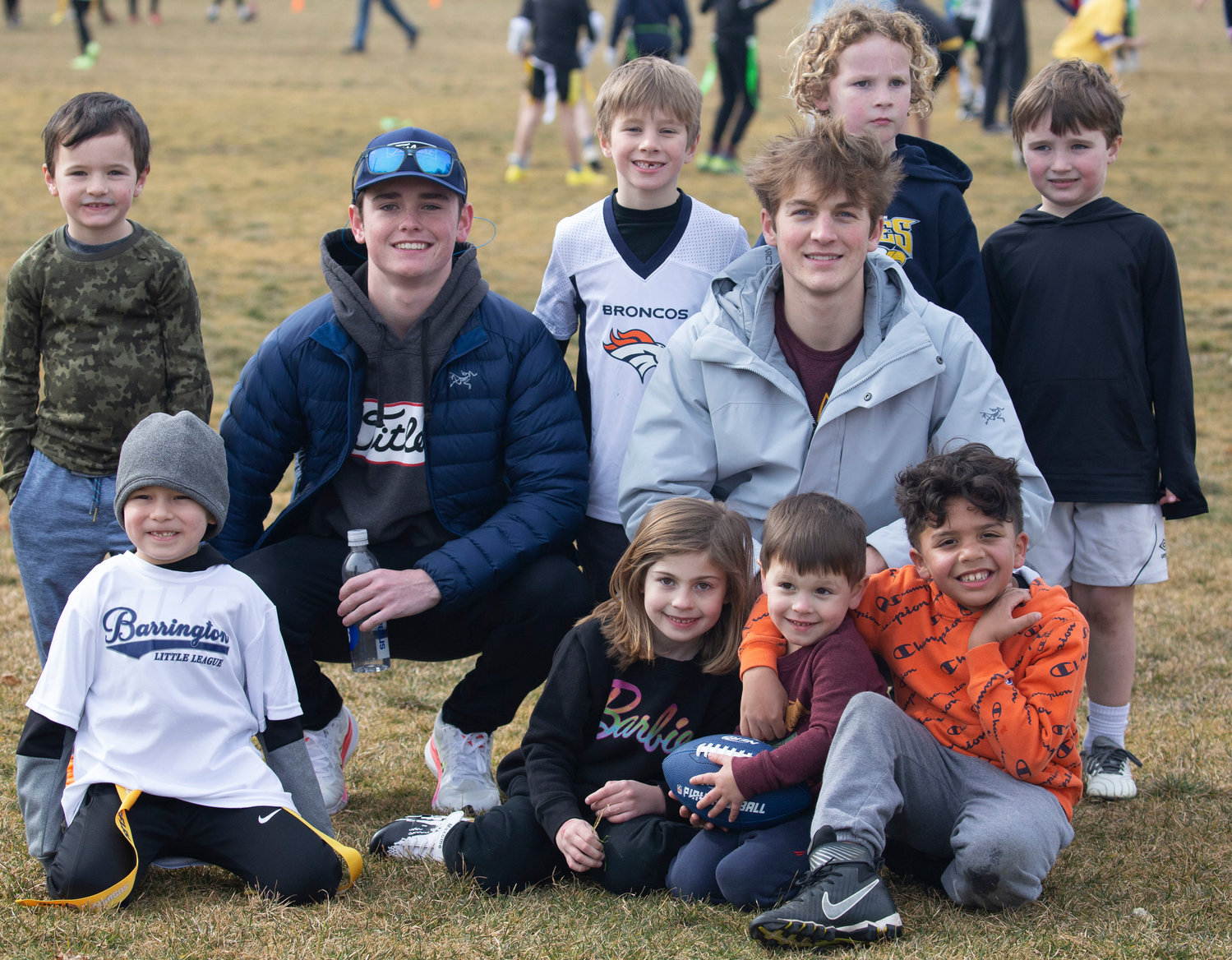 Barrington High School seniors Ryan O’Connell (left) and Harrison Cooley organized a youth flag football tournament for their Senior Projects. Here they are surrounded by children who participated in the tournament.