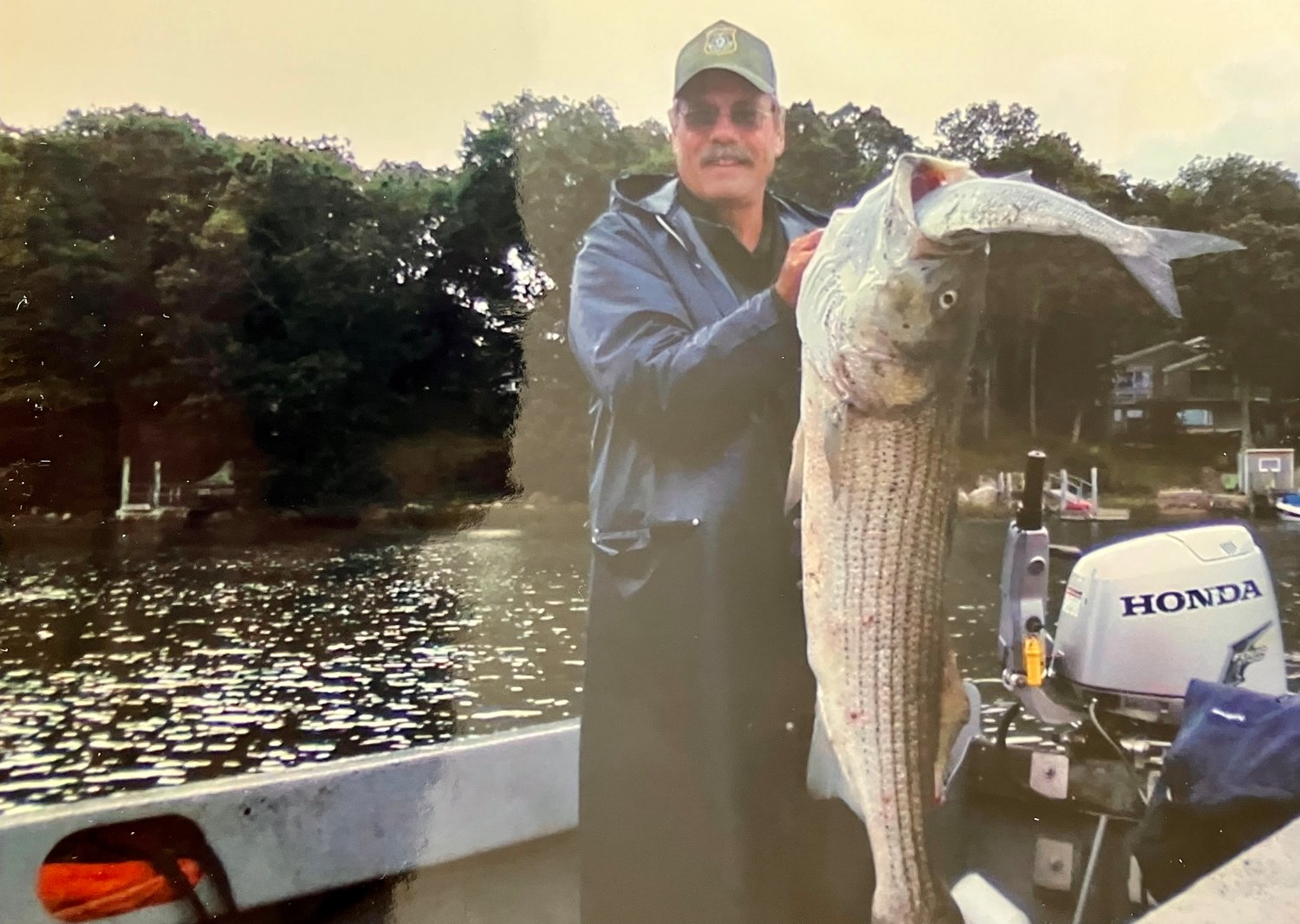 One of Janice Sherman's favorite photos of her late husband is this one taken some years ago. Helping with the annual seeding of shellfish in the Westport River one year, he spotted a big bass that had attempted to swallow a bluefish nearly its equal in size. He scooped both up over the skiff, proudly showing them off for the camera.