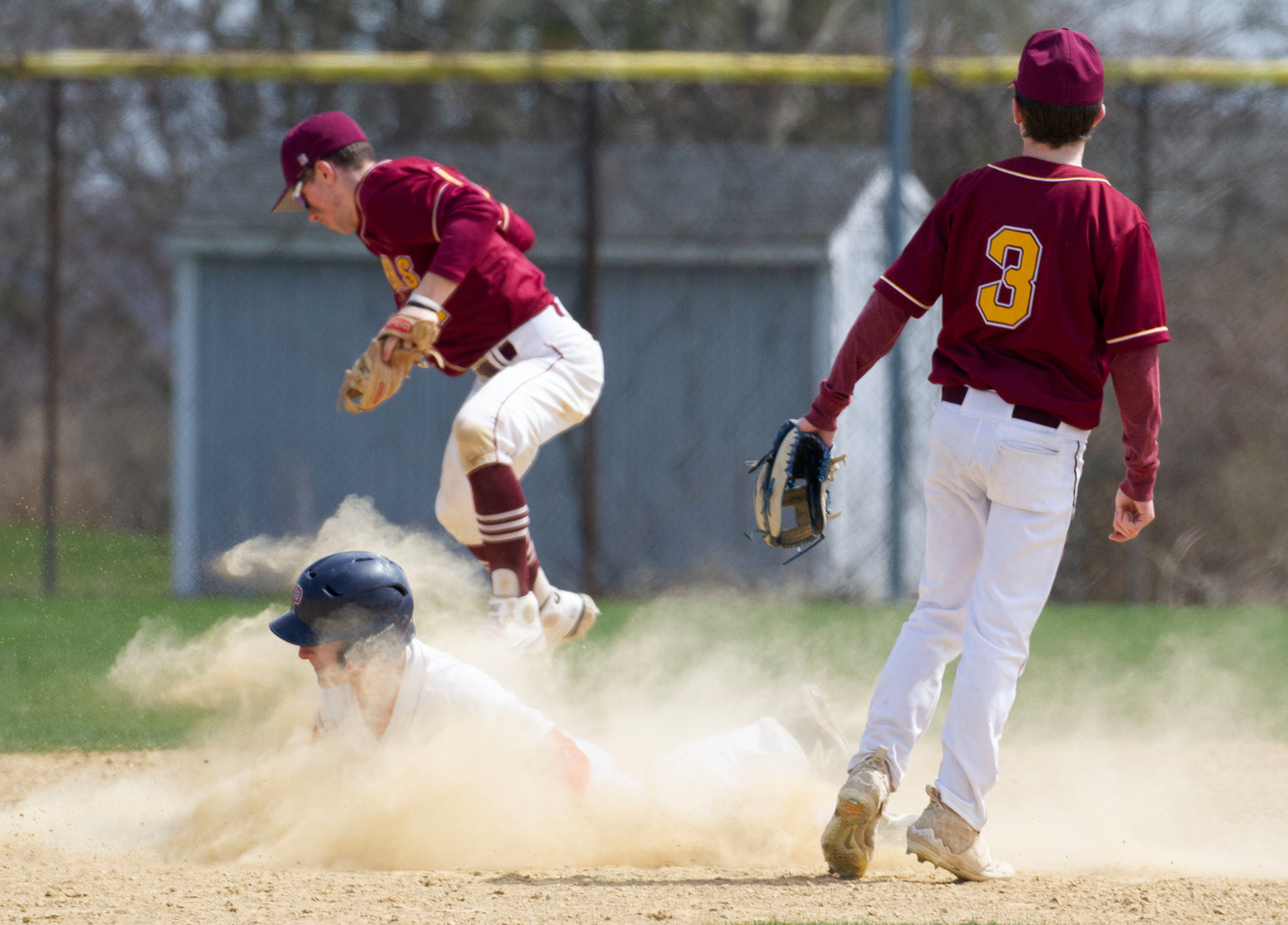 Portsmouth’s Caleb Banks dives into second base for a steal as Tiverton defenders field an errant throw by the catcher.