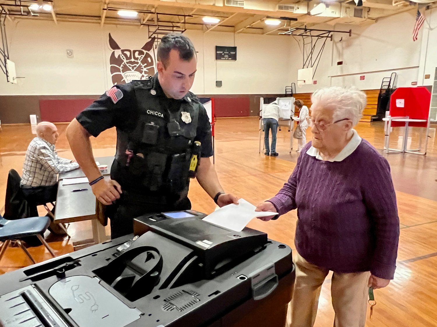 Westport police officer Mike Chicca assists a resident casting her ballot in Tuesday's election.