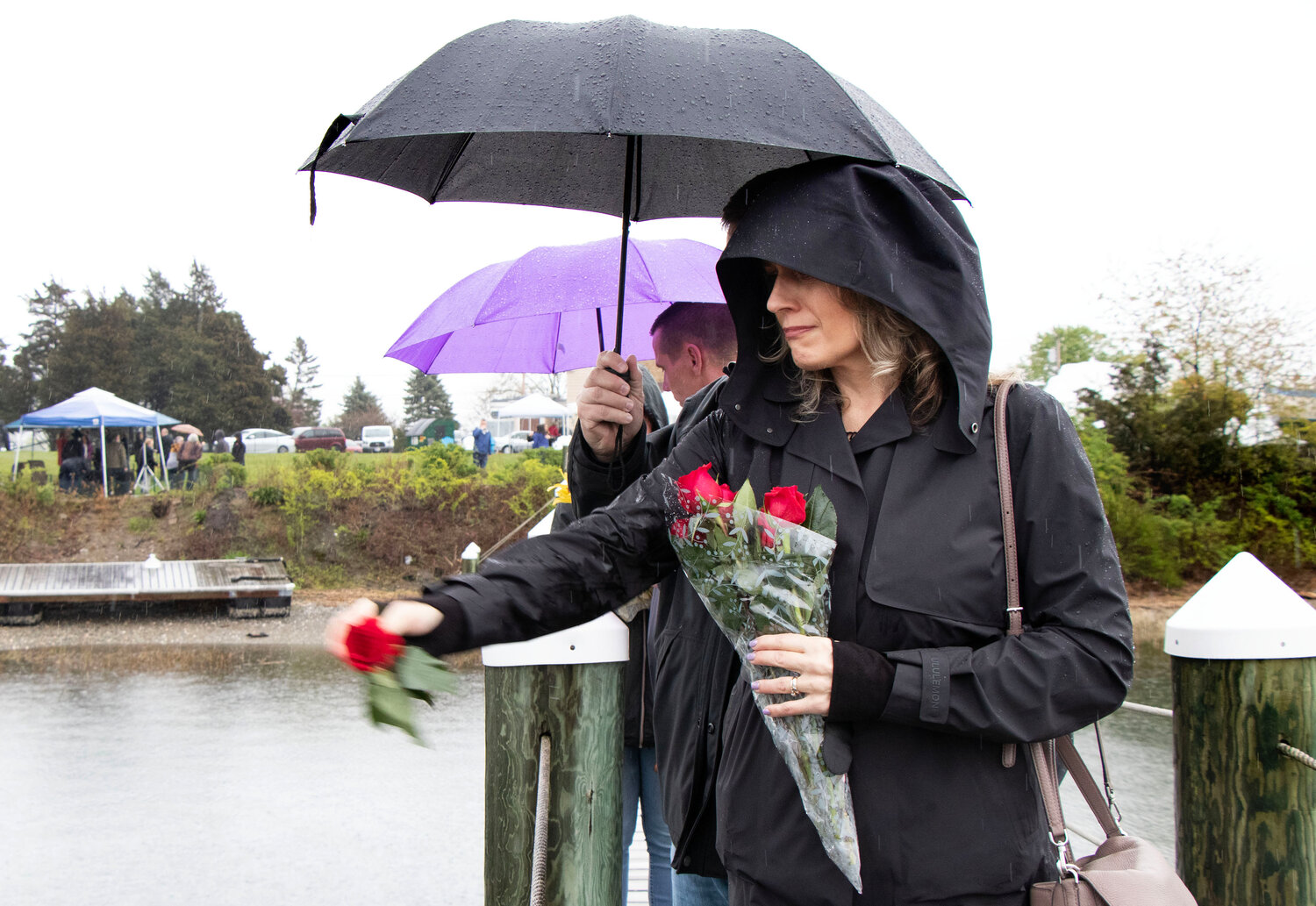 Shannon Watson tosses a rose into Blue Bill Cove Sunday afternoon in memory of her son, Cole, who died at the age of 22 after jumping from the Claiborne Pell Newport Bridge on May 7, 2022. Her husband, Tom, is behind her.